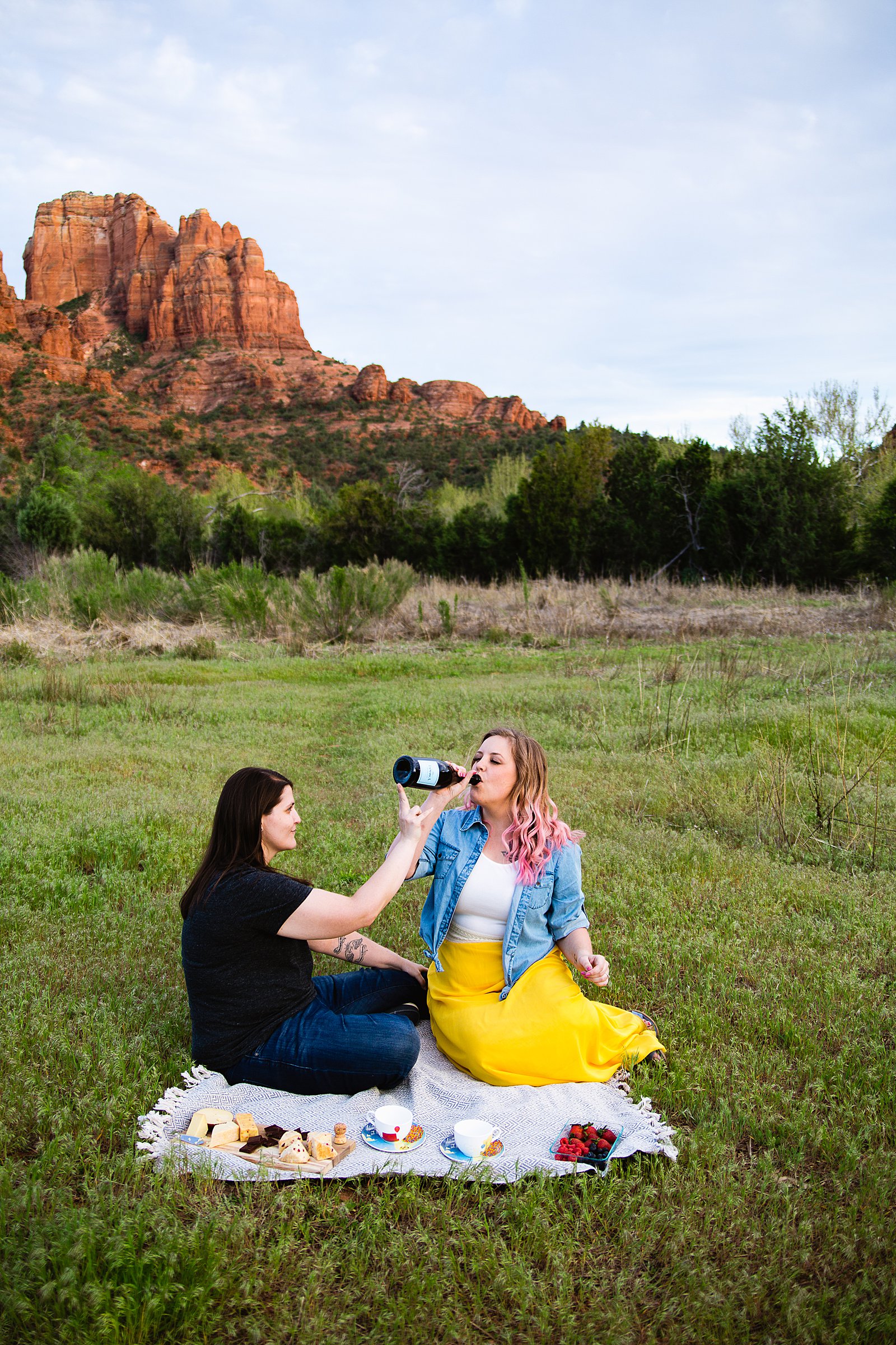 Same sex couple enjoy a picnic at Crescent Moon Ranch during their engagement session by Sedona wedding photographer PMA Photography.