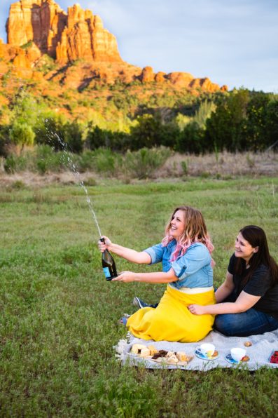 Same sex couple enjoy a picnic at Crescent Moon Ranch during their engagement session by Sedona wedding photographer PMA Photography.