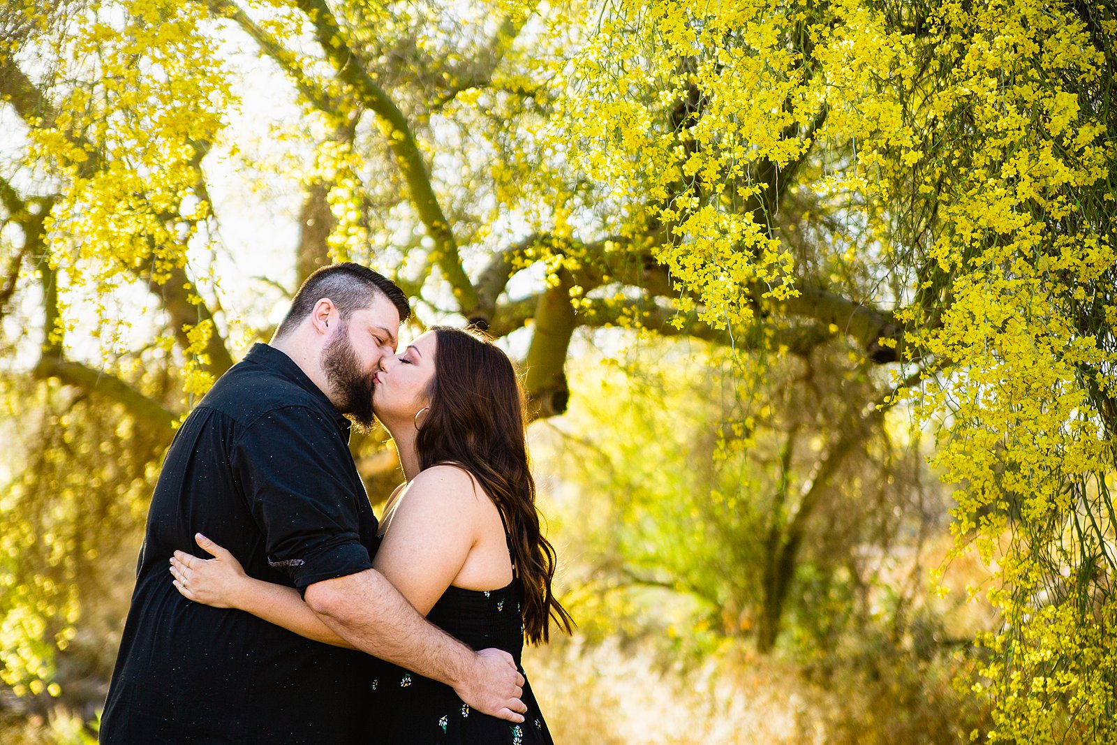Couple share a kiss during their spring Thunderbird Mountain engagement session by Phoenix wedding photographer PMA Photography.