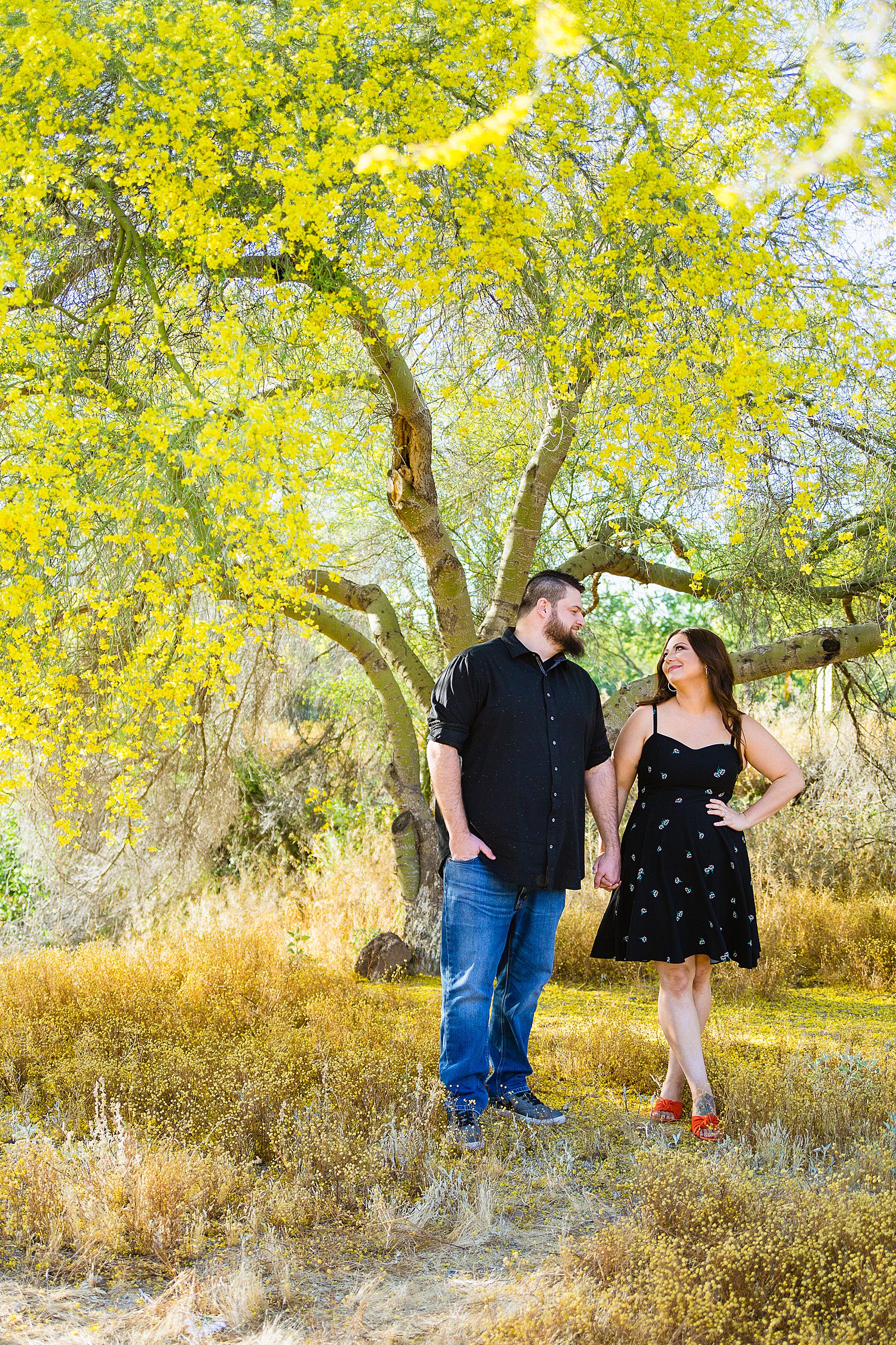 Couple look at each other during their spring Thunderbird Mountain engagement session by Phoenix wedding photographer PMA Photography.