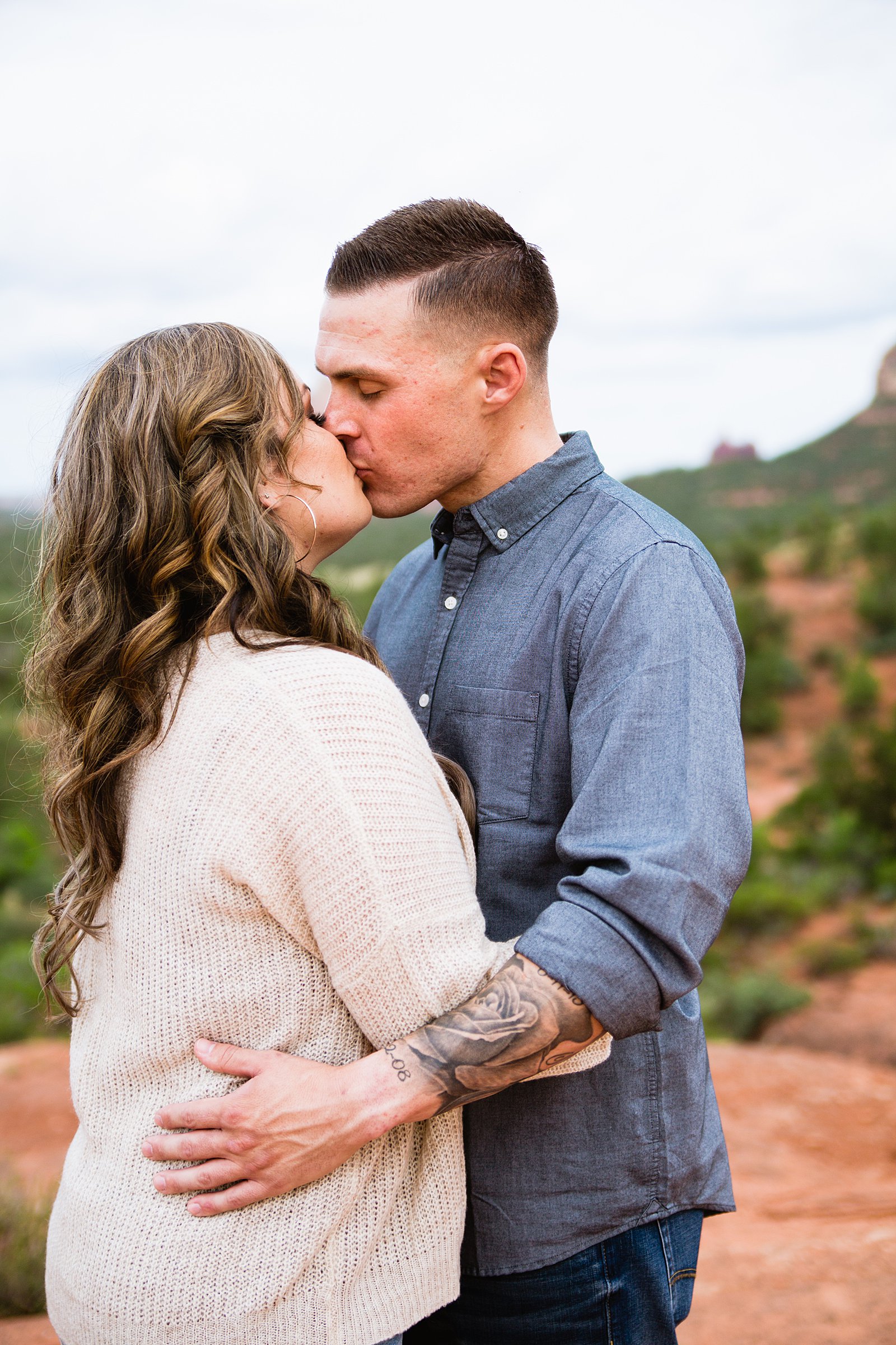Couple share a kiss during their Cathedral Rock engagement session by Sedona wedding photographer PMA Photography.