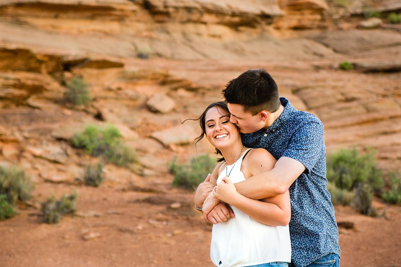 Couple laugh together during their Horshoe Bend engagement session by Page engagement photographer PMA Photography.