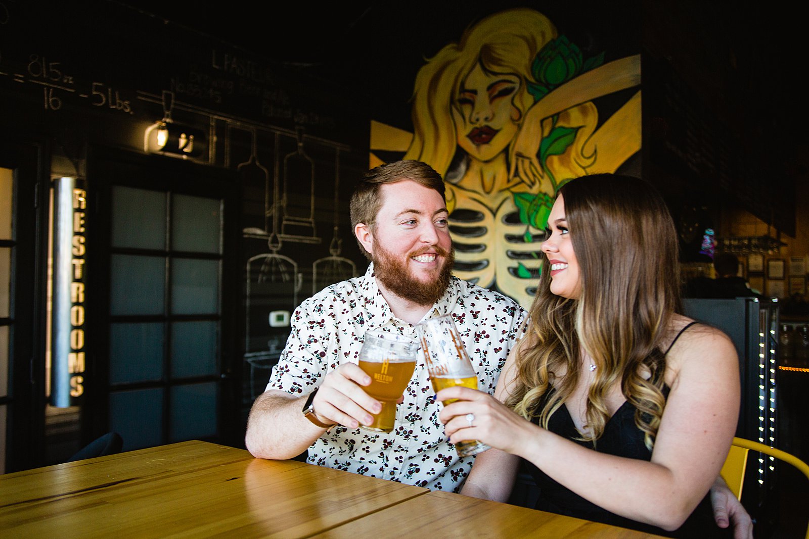 Couple share a toast during their Helton Brewery engagement session by Phoenix wedding photographer PMA Photography.