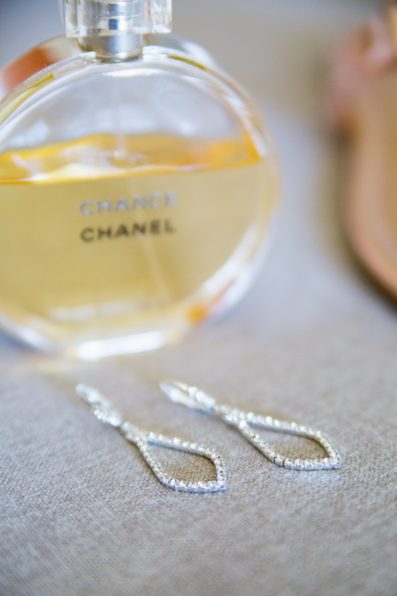 Brides's wedding day details of modern drop earrings and Chanel perfume by PMA Photography.