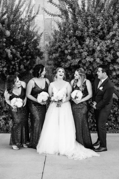Bride and mixed gender bridal party laughing together at a SoHo63 wedding by Arizona wedding photographer PMA Photography.