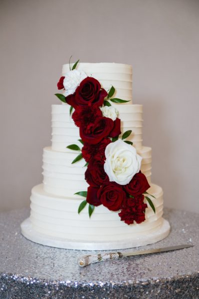 Simple modern wedding cake with white and red flowers by Arizona wedding photographer PMA Photography.