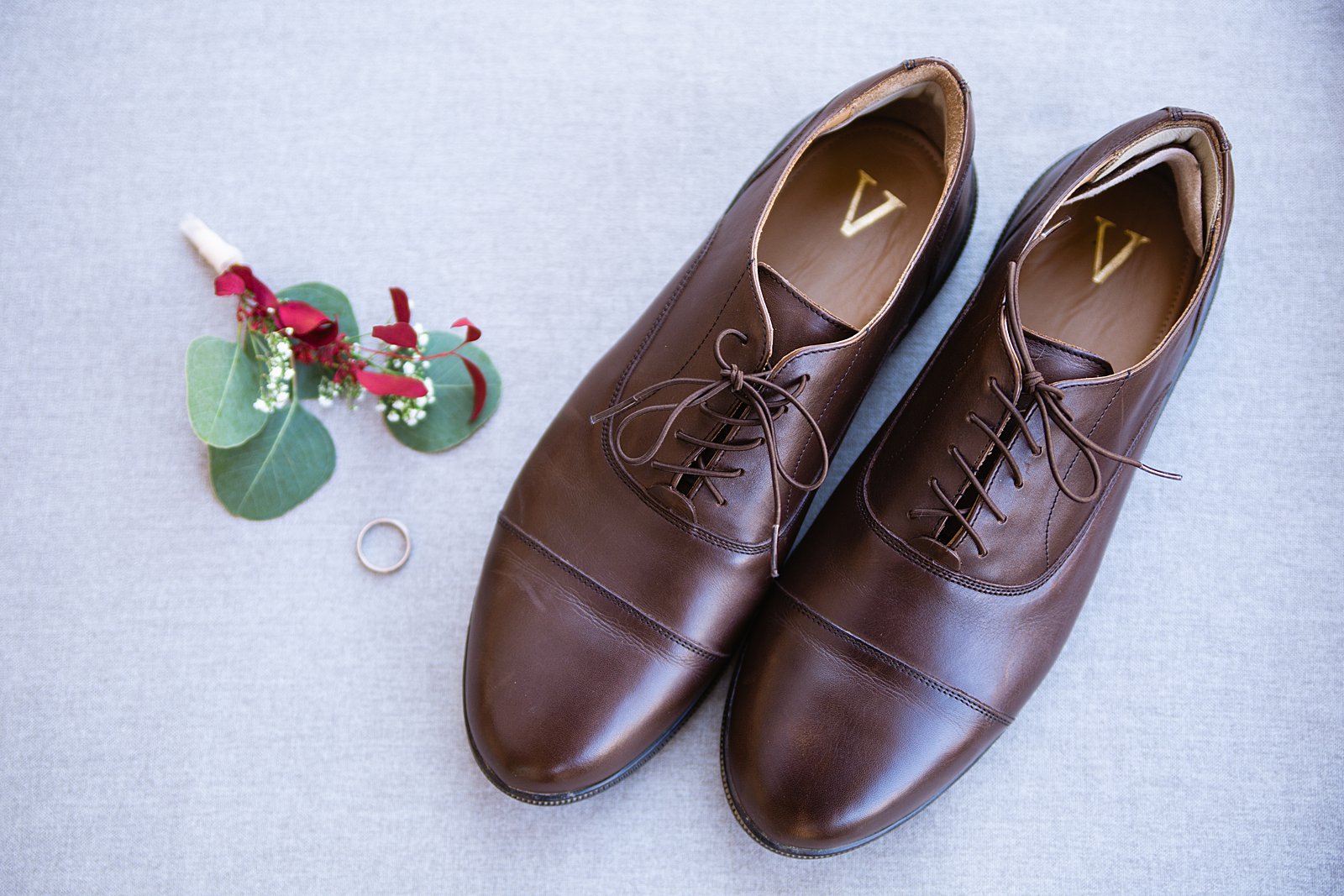 Groom's wedding day details of his wedding ring, shoes, and boutonniere by PMA Photography.