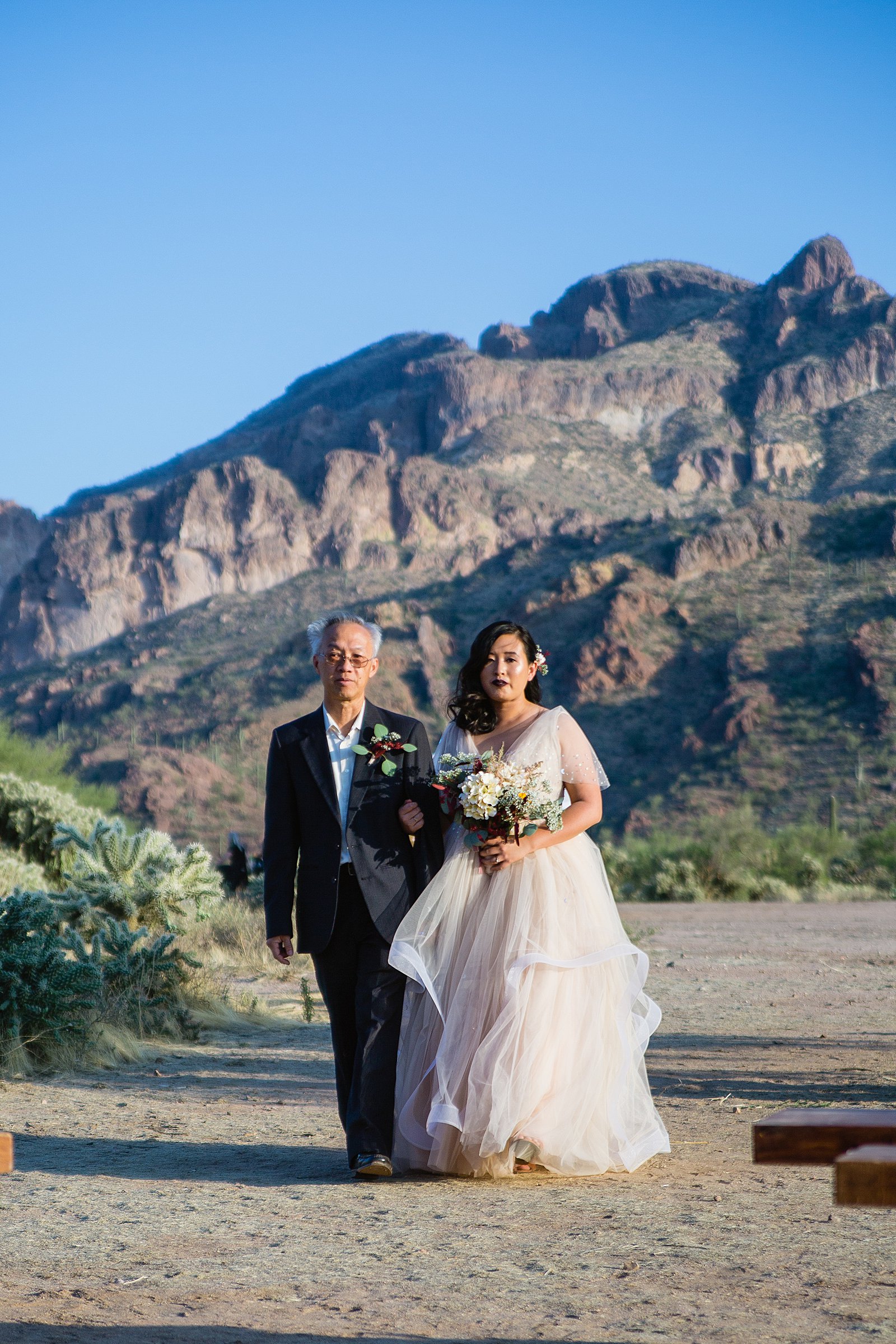 Bride walking down aisle during the Superstition Mountains wedding ceremony by Phoenix wedding photographer PMA Photography.