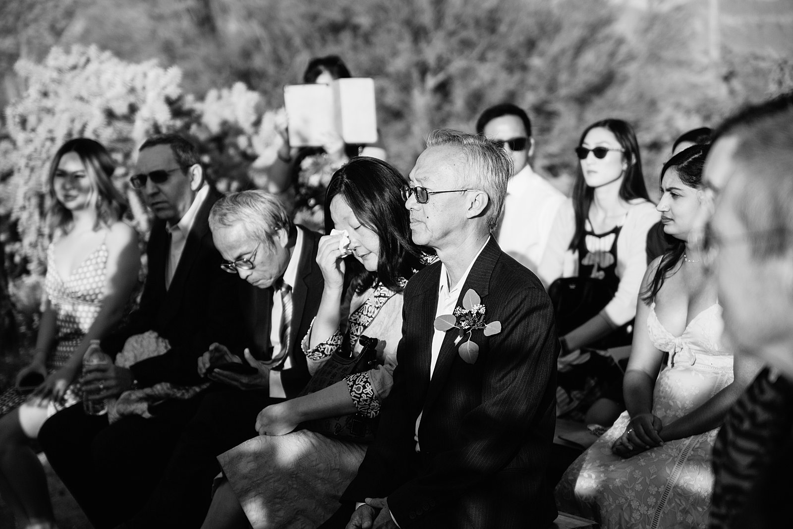 Black and white image of guests at a romantic desert wedding ceremony by PMA Photography.