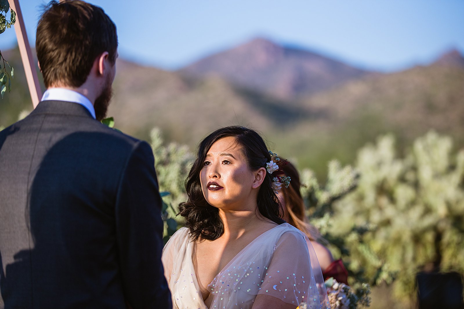 Bride looking at her groom during their wedding ceremony at the Superstition Mountains by Mesa wedding photographer PMA Photography.