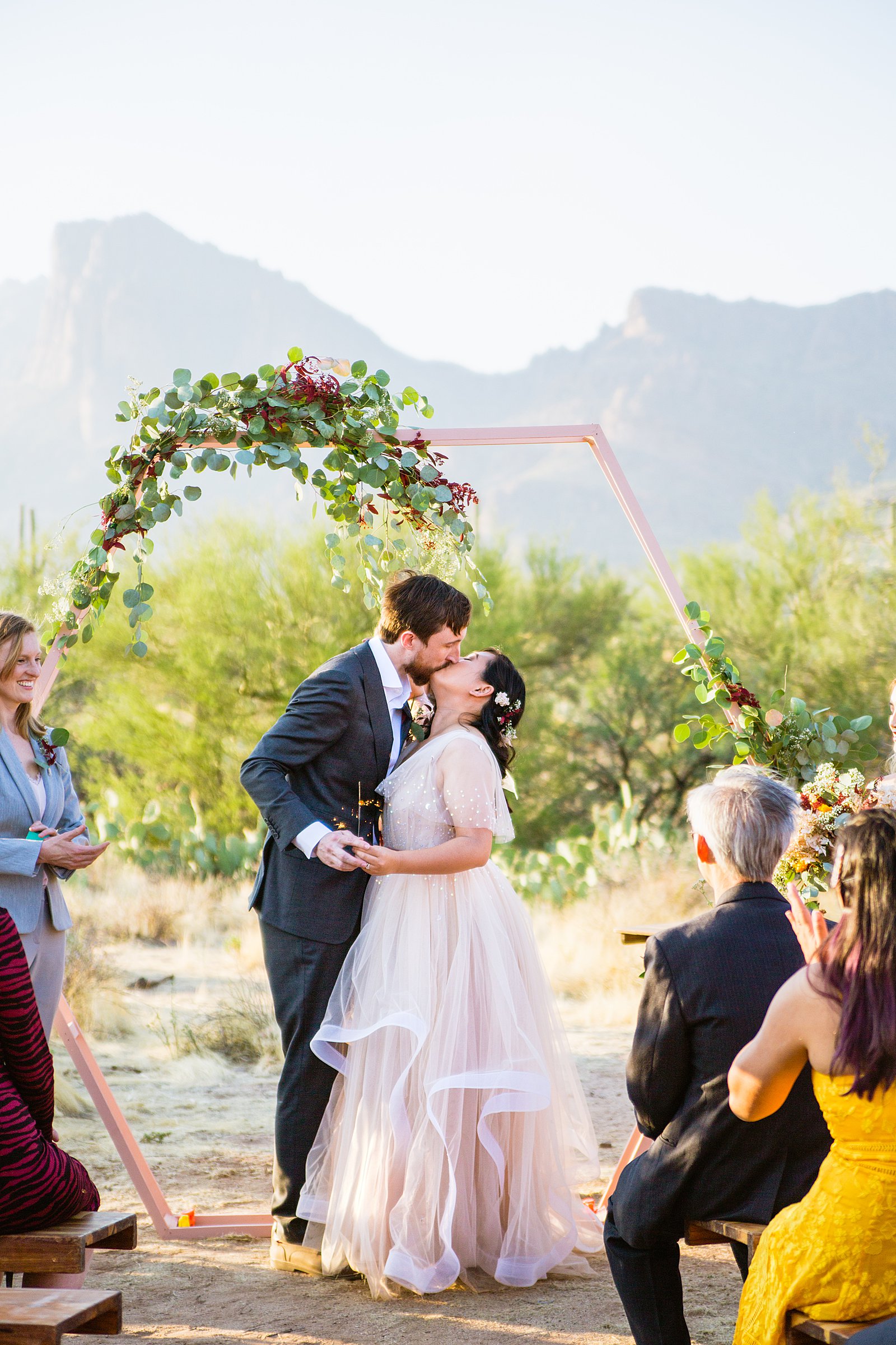 Bride and Groom share their first kiss during their wedding ceremony at the Superstition Mountains by Arizona wedding photographer PMA Photography.