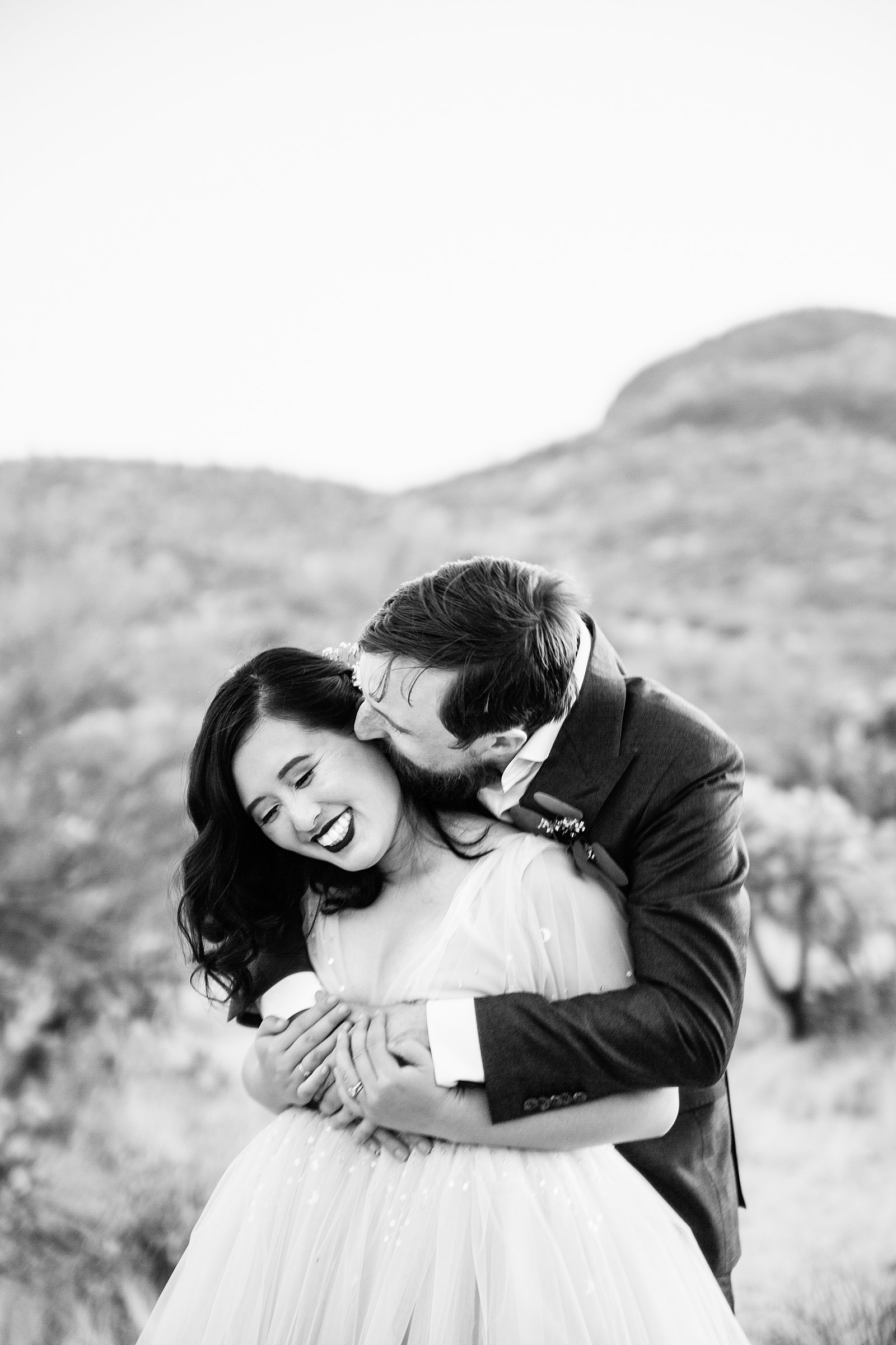 Bride and Groom laughing together during their Superstition Mountain Cloth and Flame wedding by Arizona wedding photographer PMA Photography.