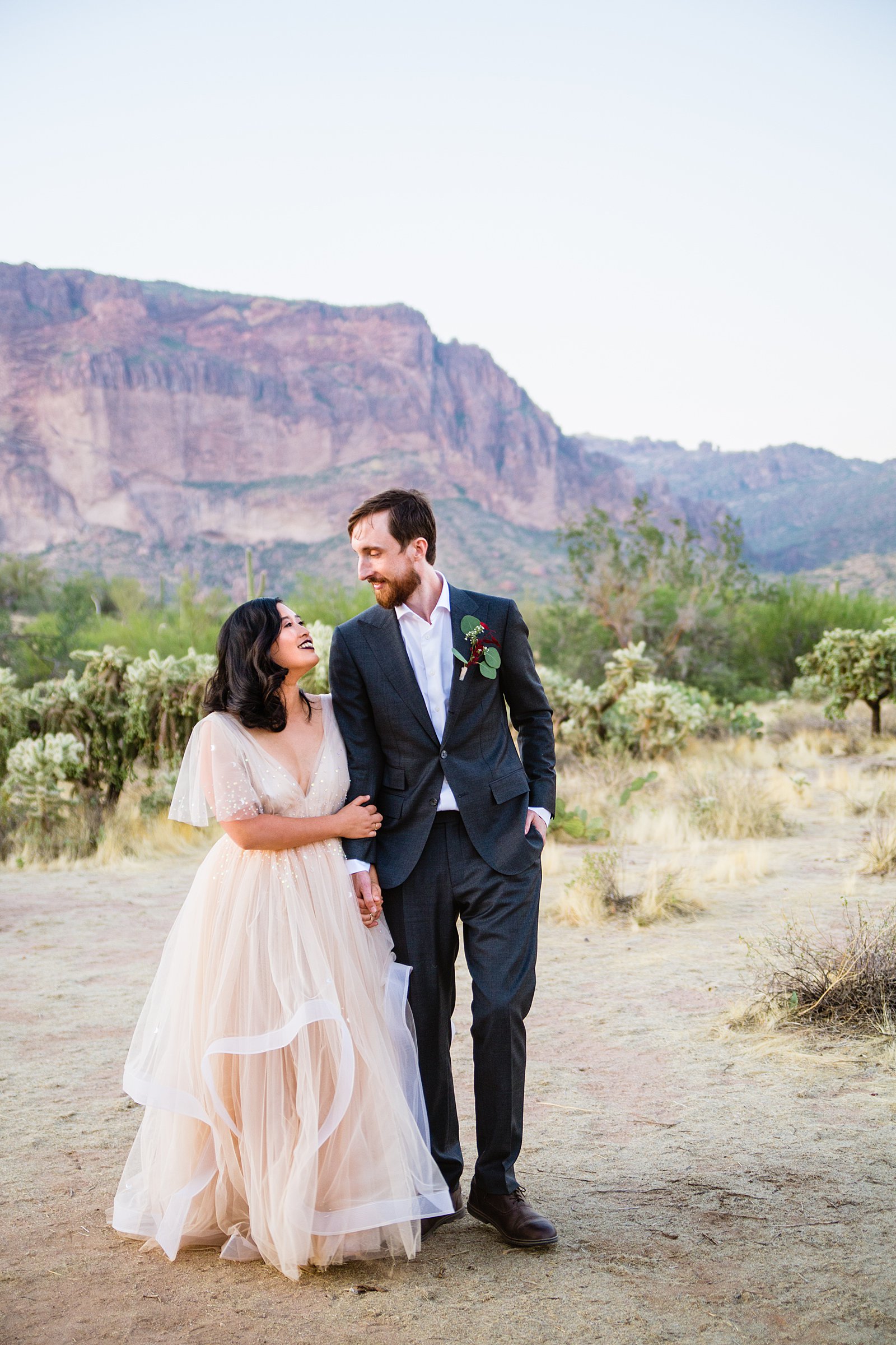 Bride and Groom walking together during their Superstition Mountain Cloth and Flame wedding by Mesa wedding photographer PMA Photography.