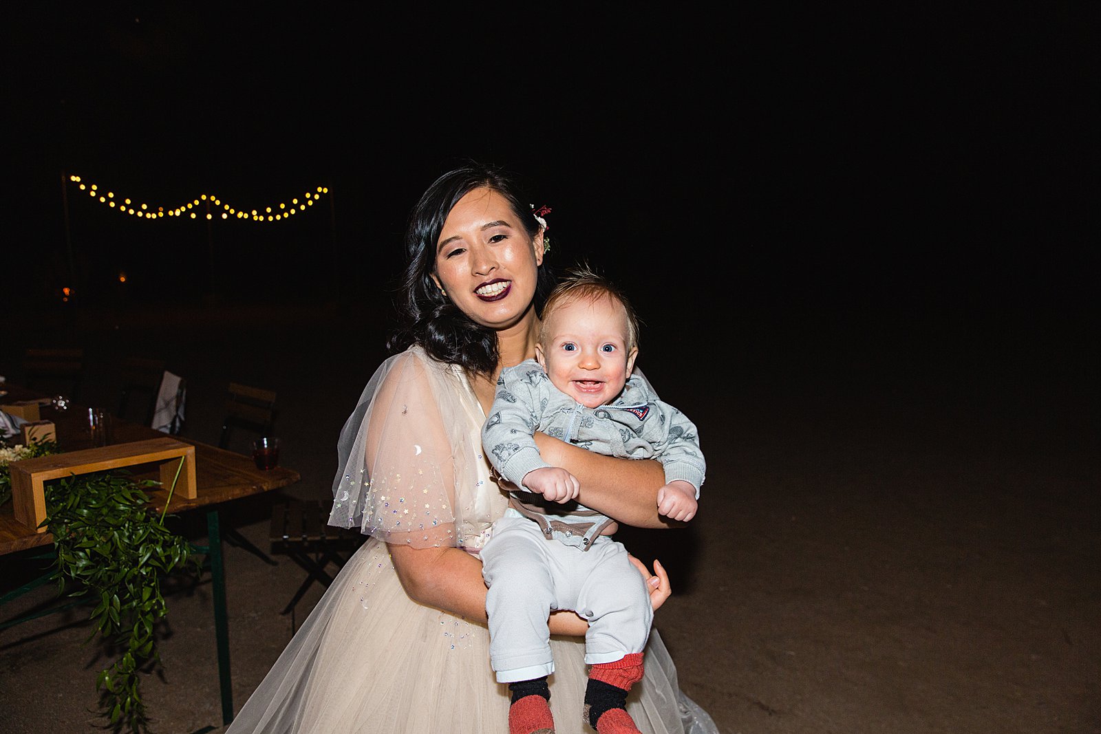 Bride posing with new nephew at a Cloth and Flame wedding reception by Phoenix wedding photographer PMA Photography.