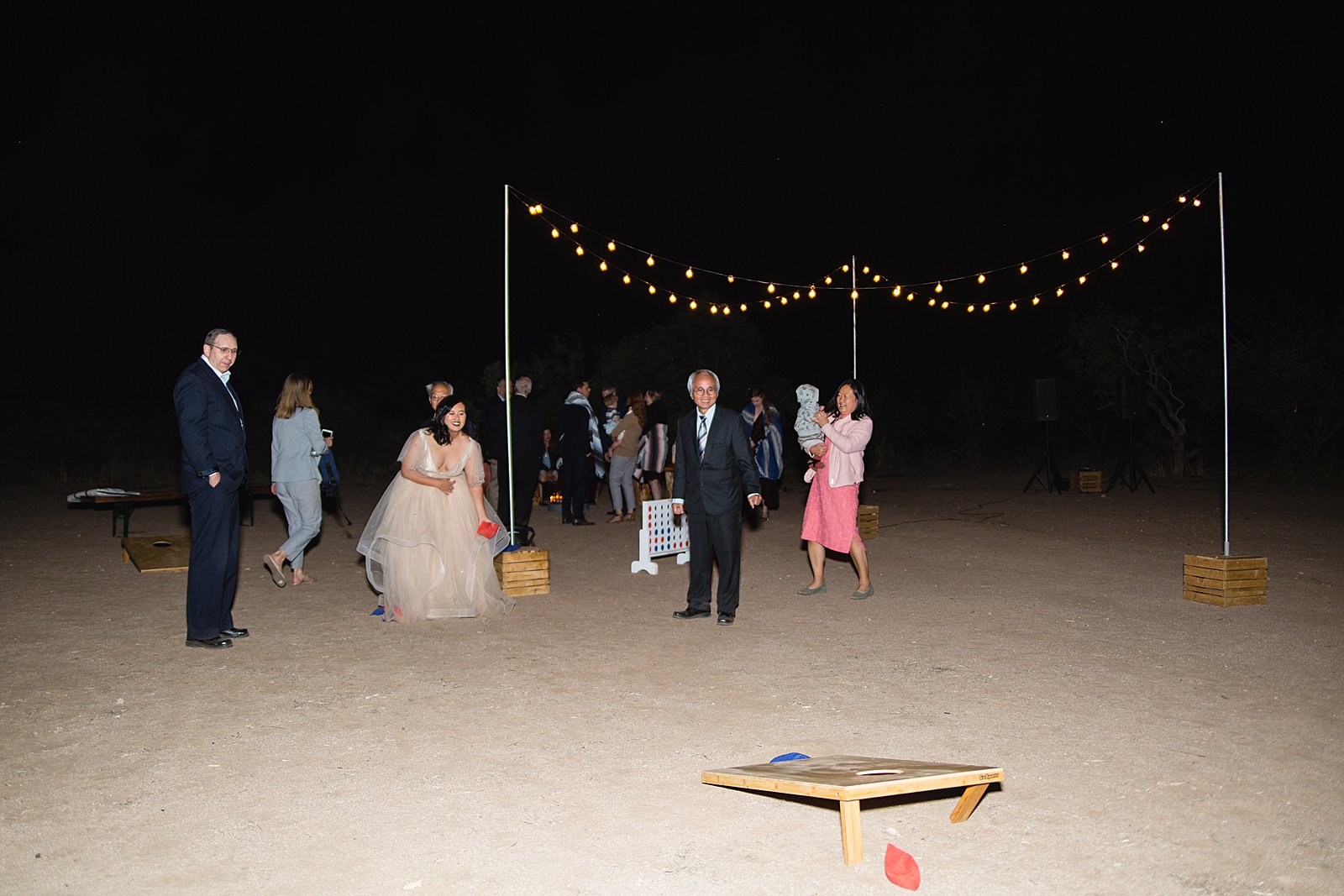 Bride playing cornhole with guests at a Cloth and Flame wedding reception by Phoenix wedding photographer PMA Photography.