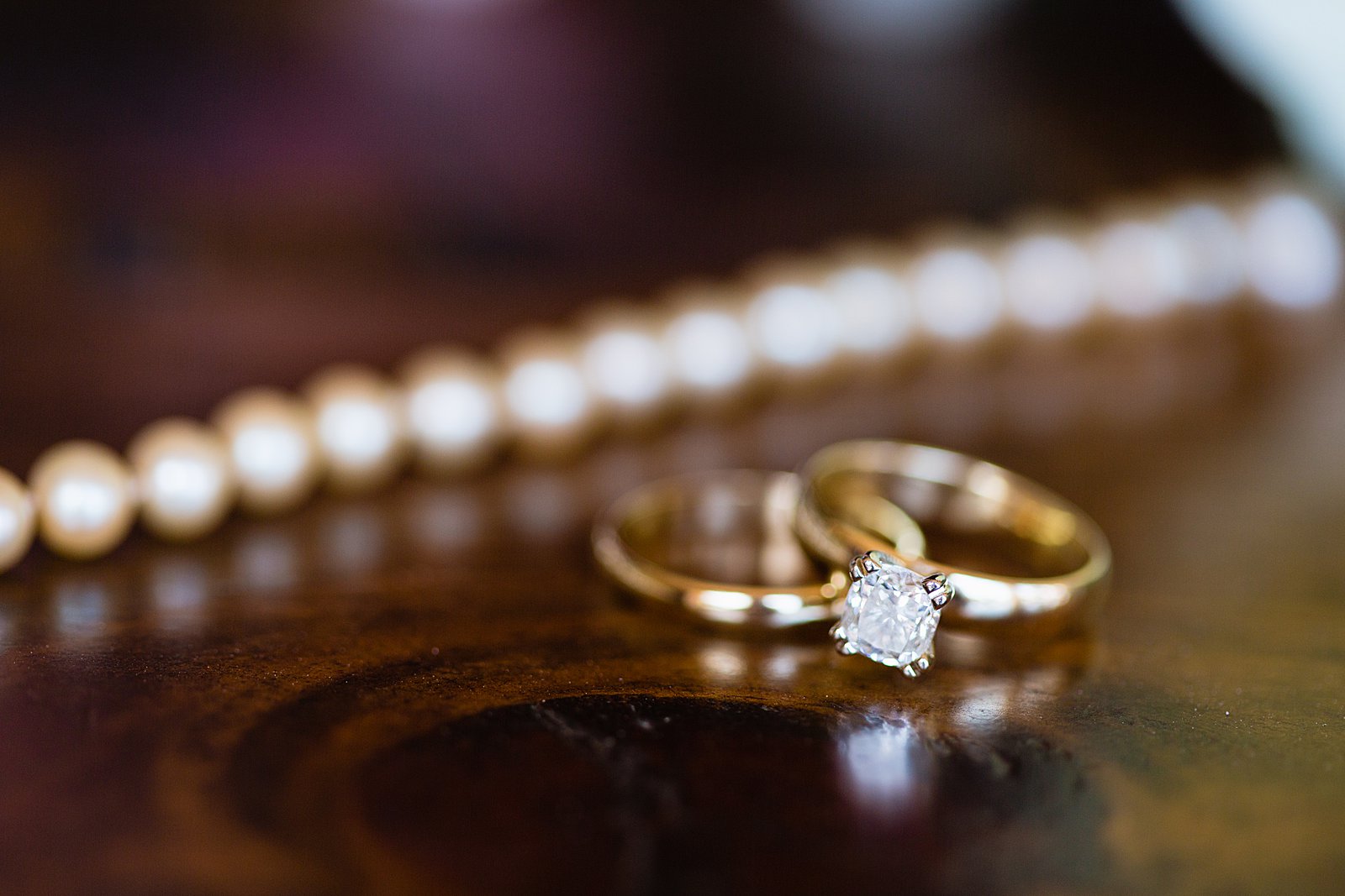 Brides's wedding day details of a simple gold wedding ring set and a pearl bracelet by PMA Photography.