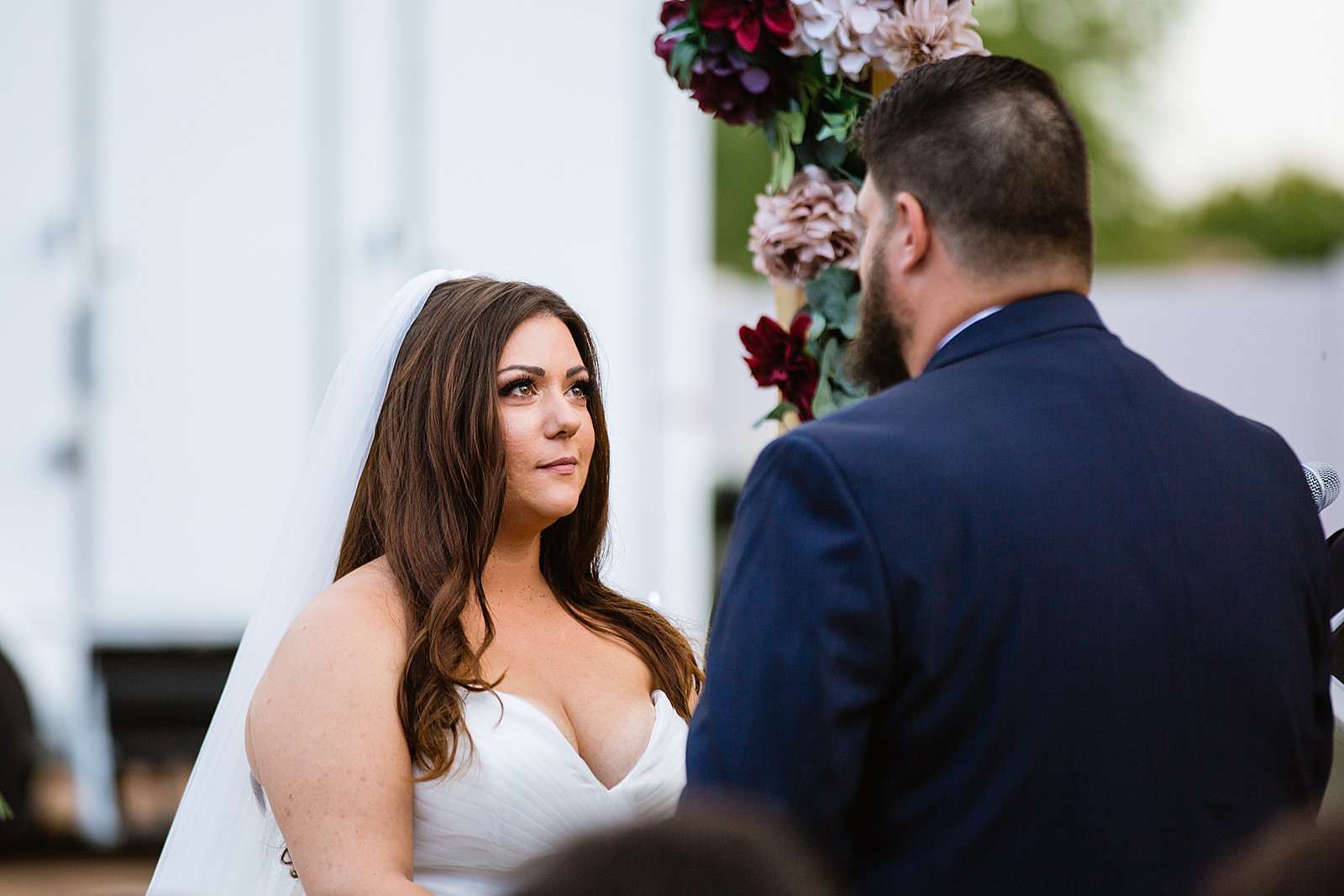 Bride looking at her groom during their wedding ceremony at an Arizona backyard by Tempe wedding photographer PMA Photography.