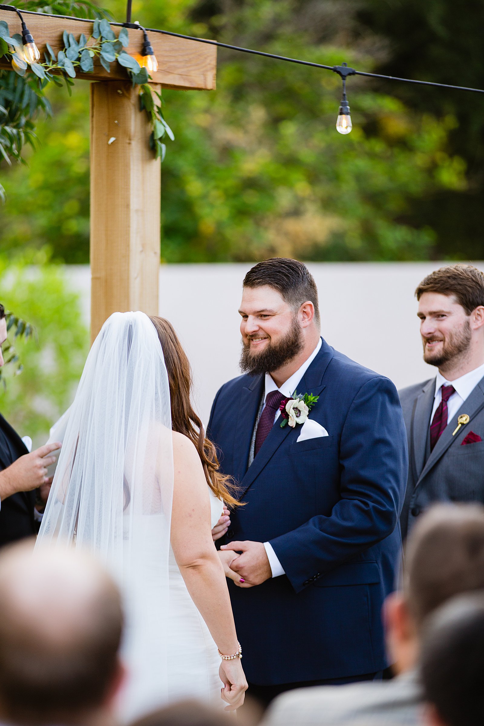 Groom looking at his bride during their wedding ceremony at an Arizona backyard by Tempe wedding photographer PMA Photography.