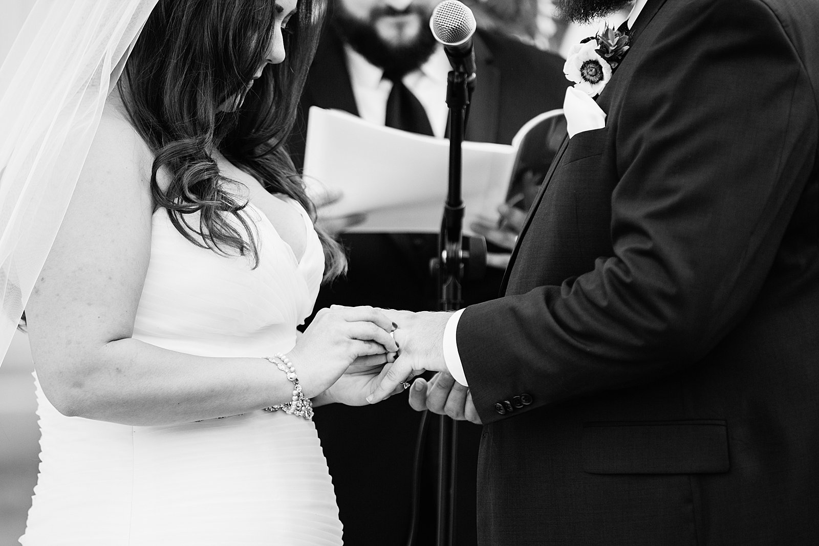 Bride and Groom exchange rings during their wedding ceremony at an Arizona backyard by Phoenix wedding photographer PMA Photography.