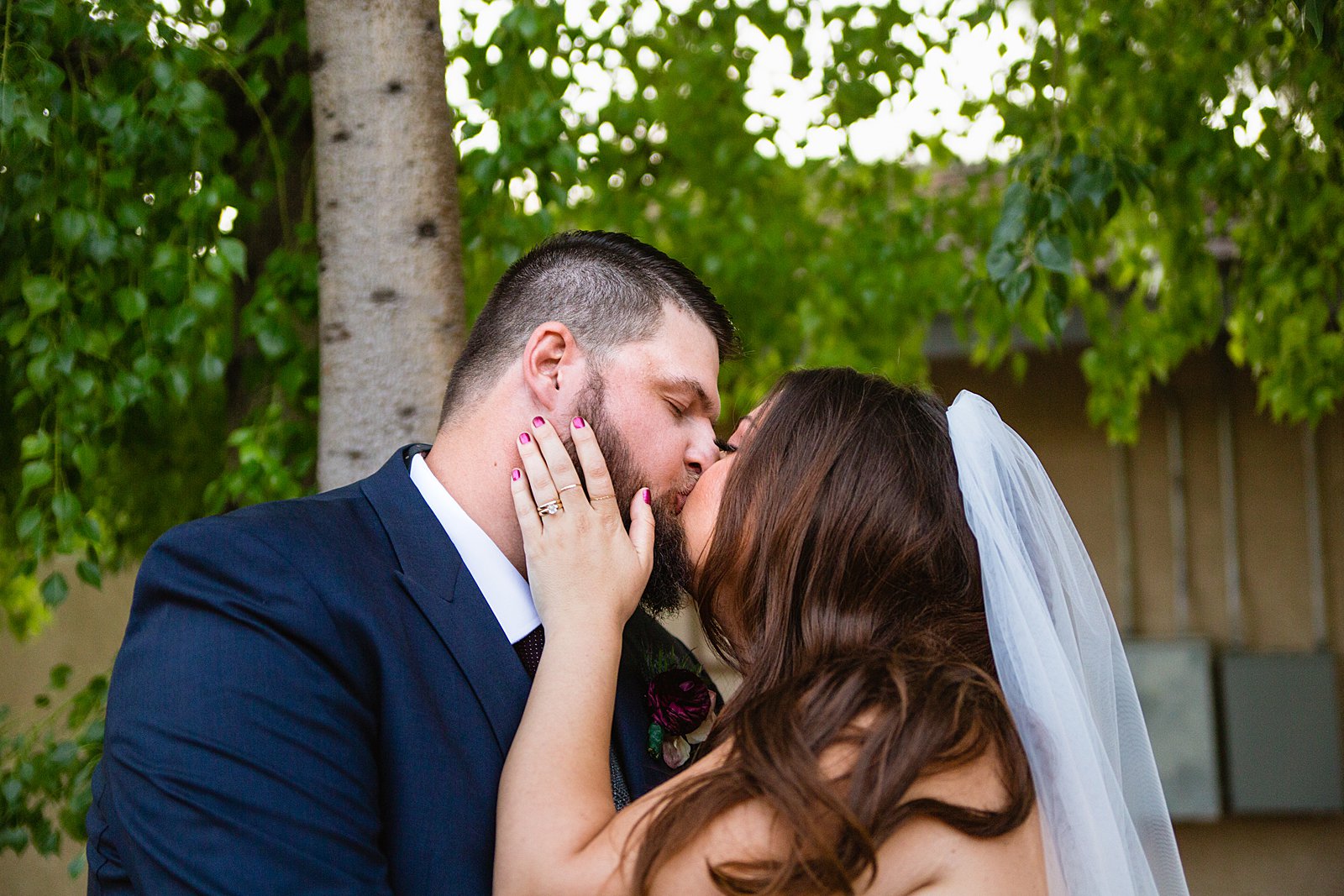 Bride and Groom share a kiss during their Arizona backyard wedding by Tempe wedding photographer PMA Photography.