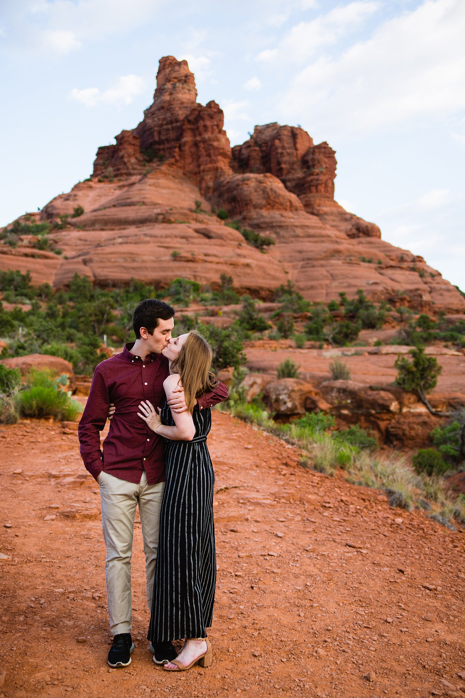 Couple share a kiss during their Bell Rock engagement session by Sedona wedding photographer PMA Photography.
