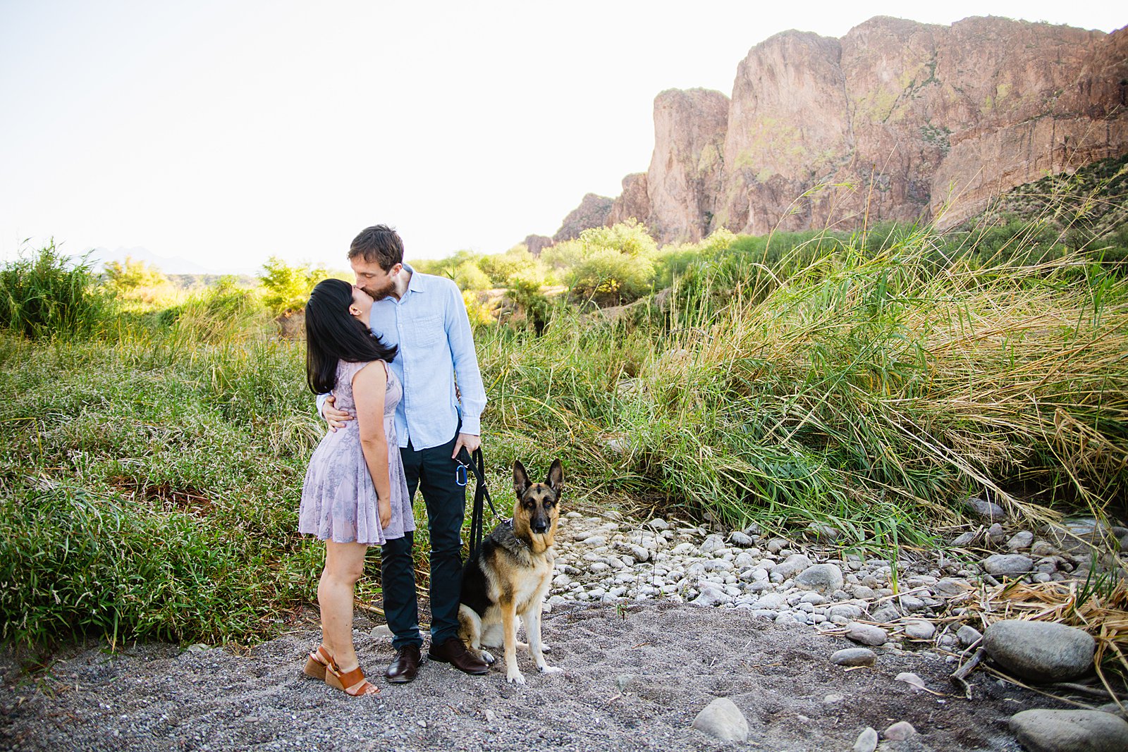 Couple share a kiss with their dog during their Salt River engagement session by Phoenix wedding photographer PMA Photography.