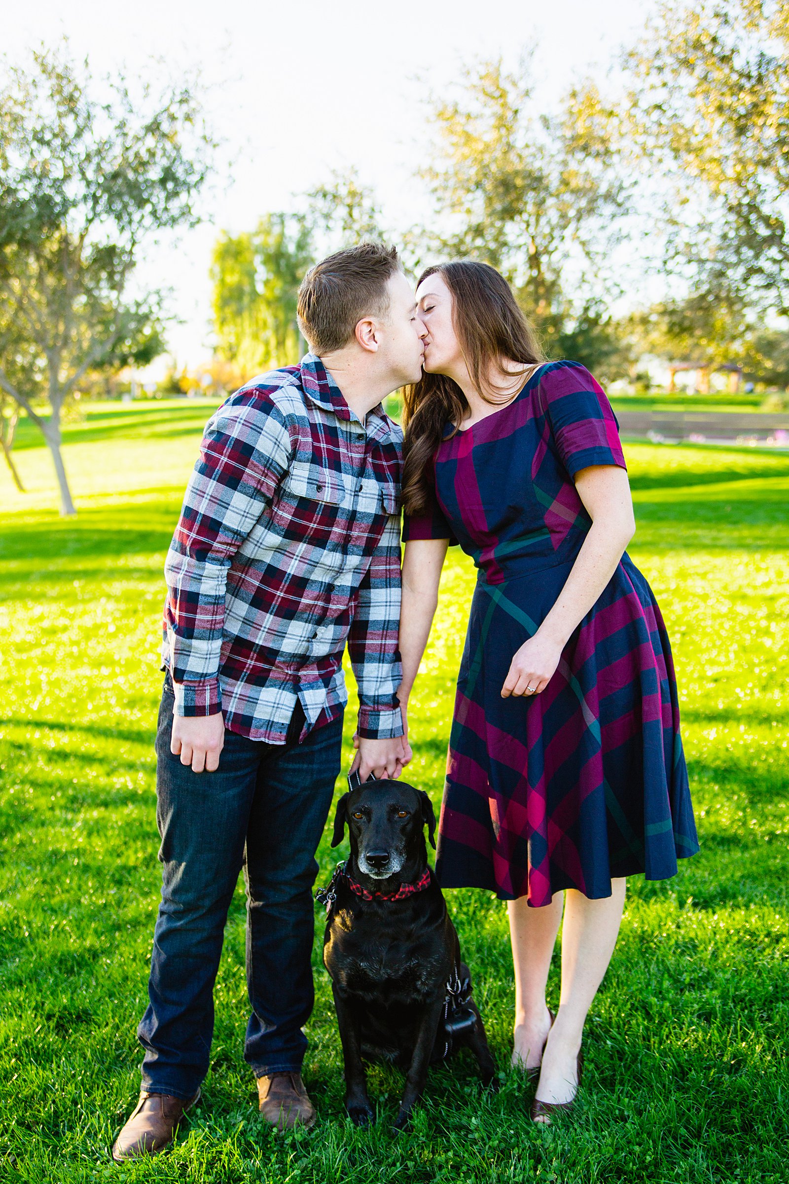 Couple share a kiss with their dog during their Phoenix engagement session by Arizona wedding photographer PMA Photography.