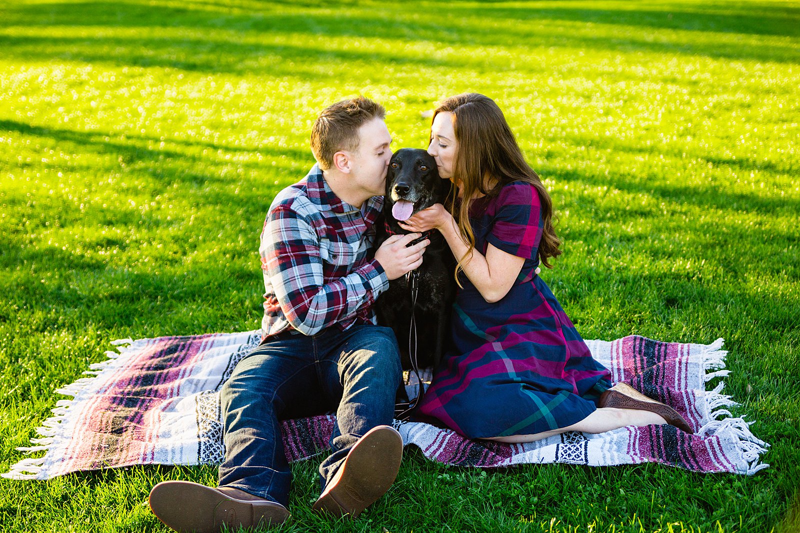 Couple share a kiss with their dog during their Phoenix engagement session by Arizona wedding photographer PMA Photography.