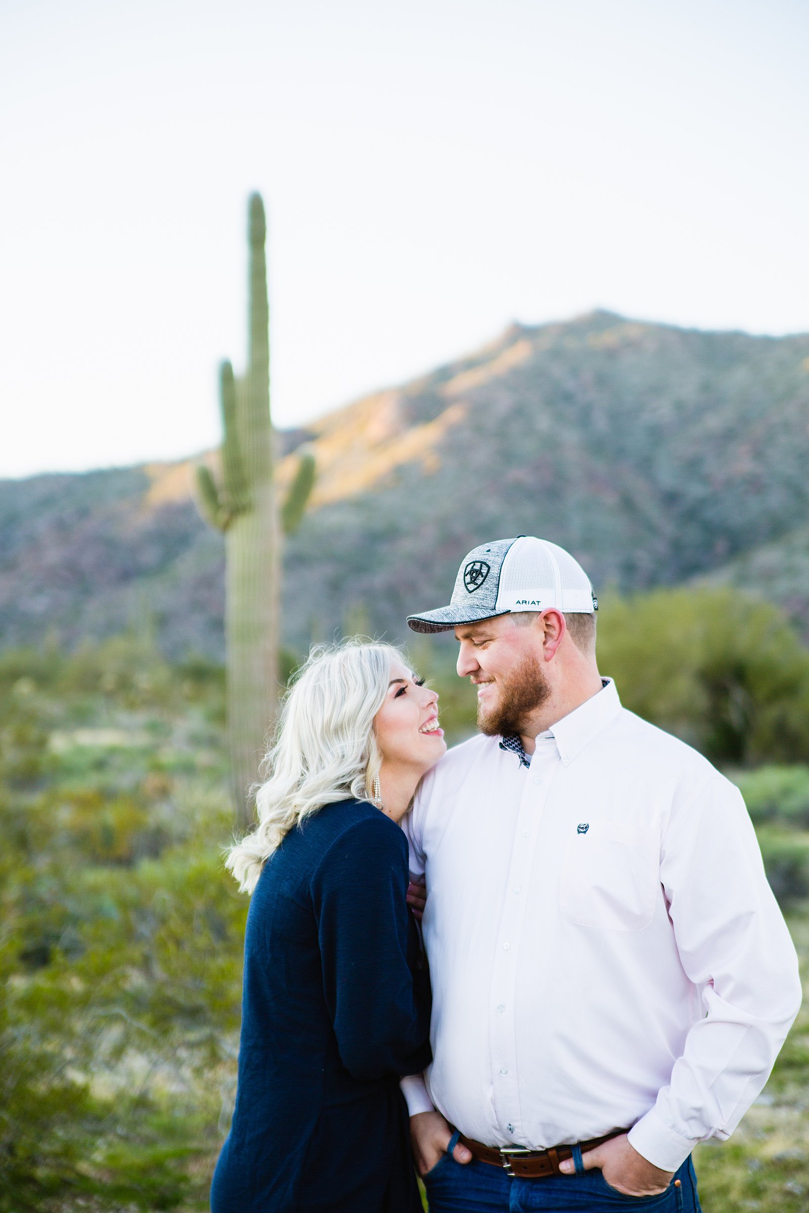 Couple look at each other during their White Tanks engagement session by Phoenix wedding photographer PMA Photography.