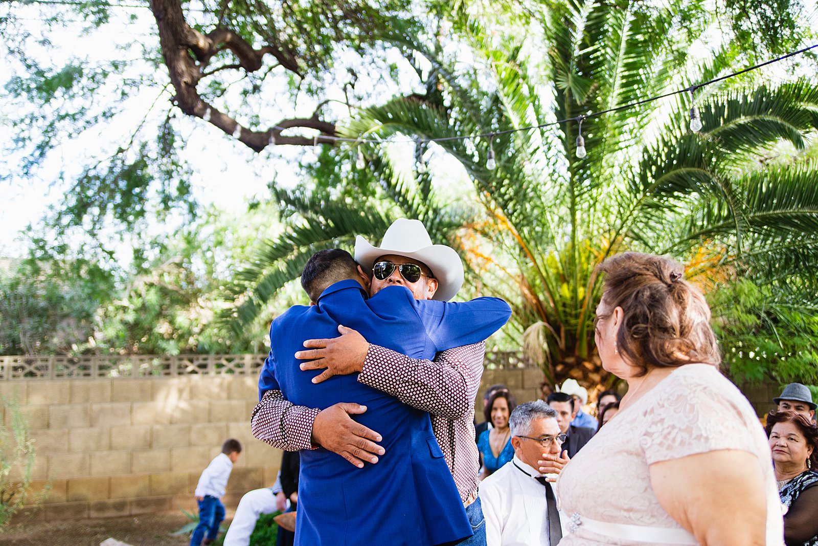 Groom hugging his parents during Valley Garden Center wedding ceremony by Phoenix wedding photographer PMA Photography.