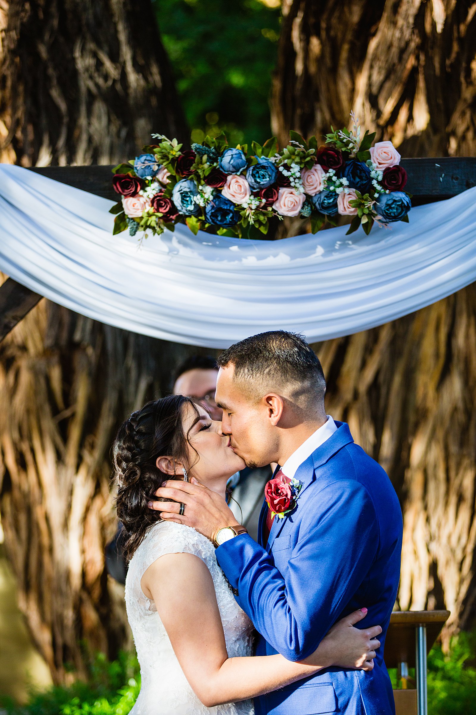 Bride and Groom share their first kiss during their wedding ceremony at Valley Garden Center by Arizona wedding photographer PMA Photography.