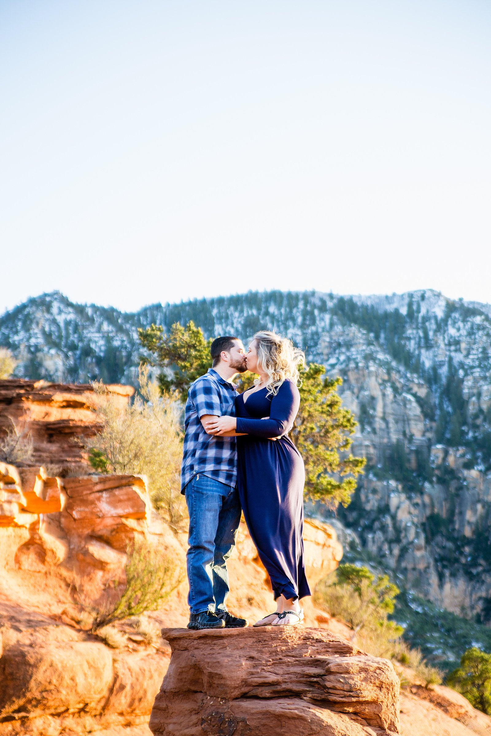 Adventurous couple share an intimate moment during their Merry Go Round Rock engagement session by Sedona engagement photographer PMA Photography.