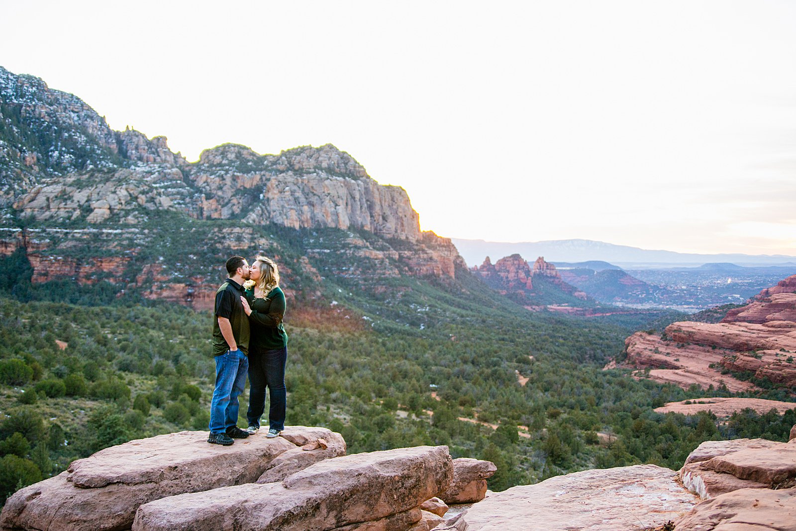 Adventurous couple share a kiss during their Merry Go Round Rock engagement session by Sedona wedding photographer PMA Photography.