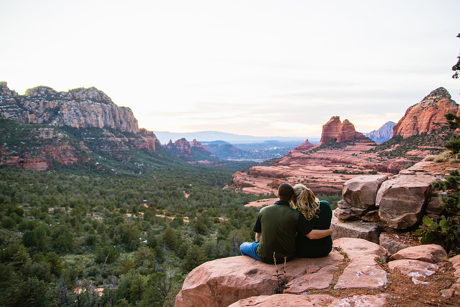 Adventurous couple watching the sunset together during their Sedona engagement session by Arizona engagement photographer PMA Photography.
