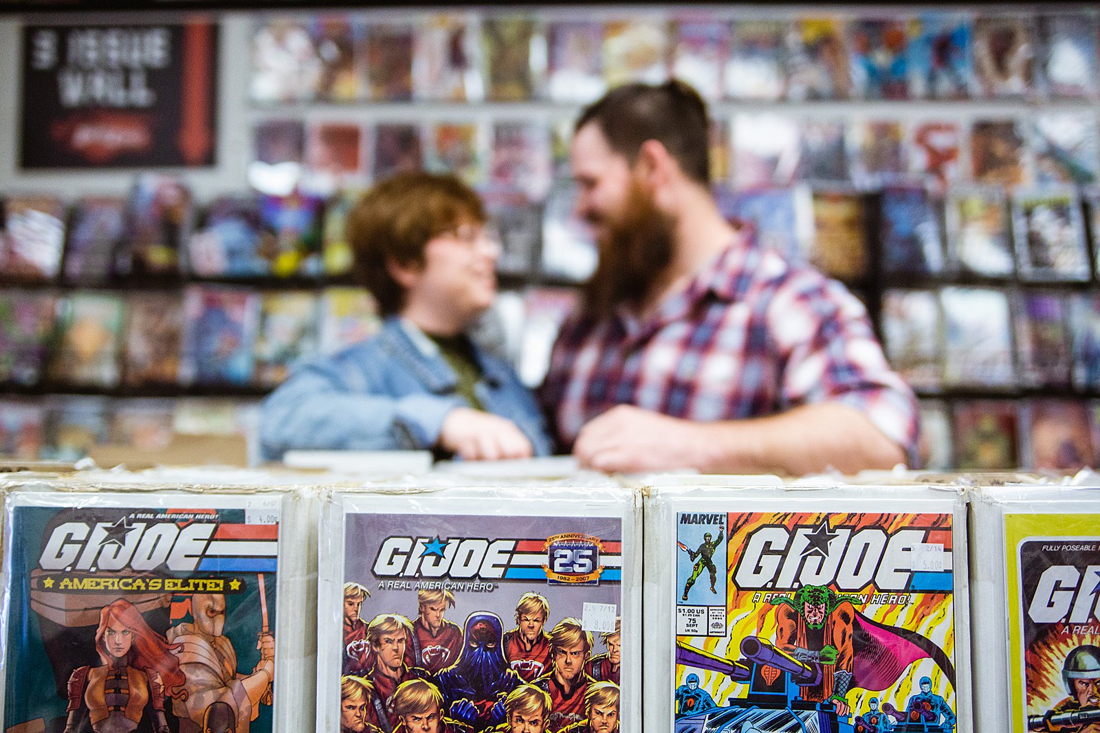 Couple look through comics together during their Comic Book Store engagement session by Glendale engagement photographer PMA Photography.