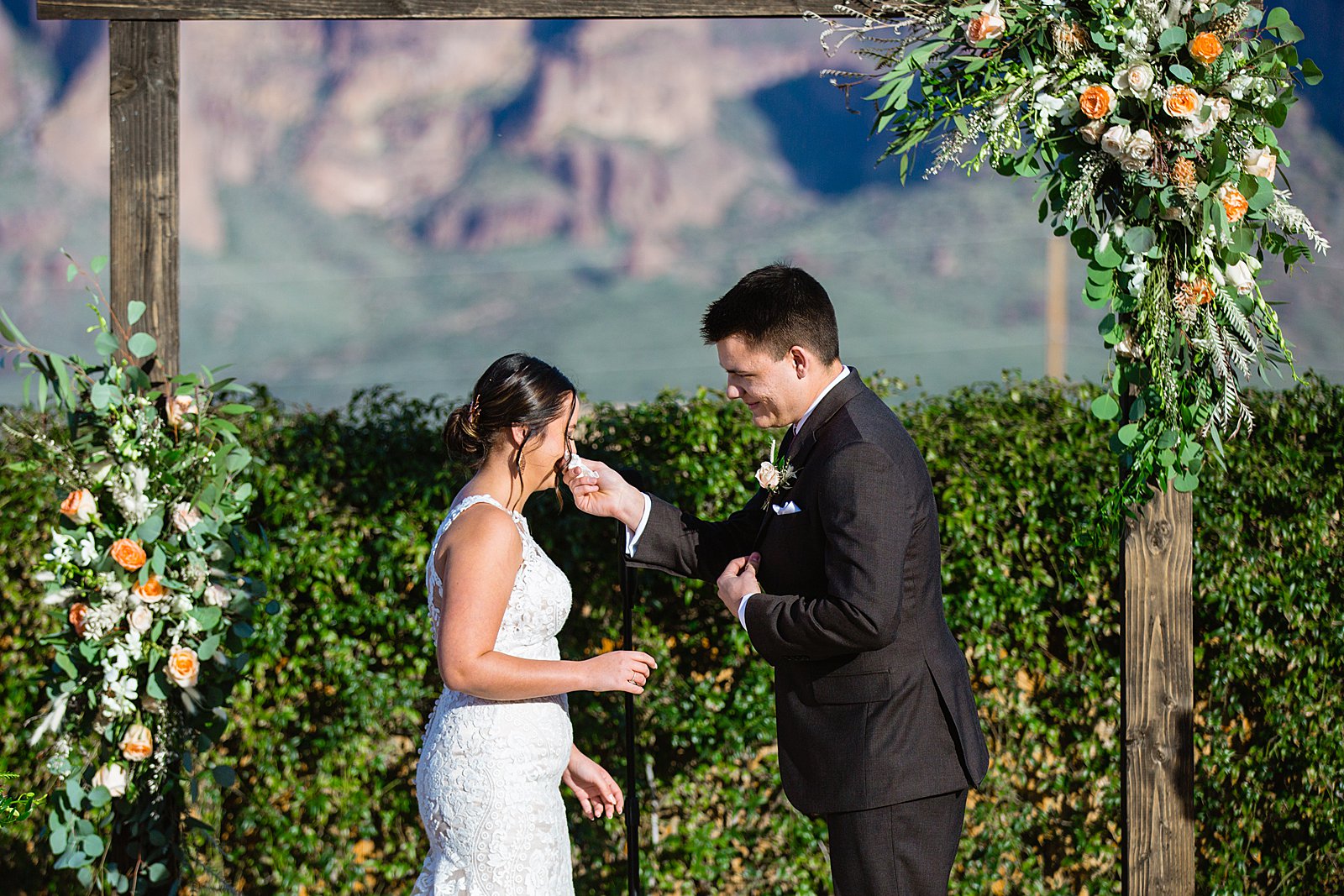 Groom wiping his bride's tears during their wedding ceremony at The Paseo by Apache Junction wedding photographer PMA Photography.