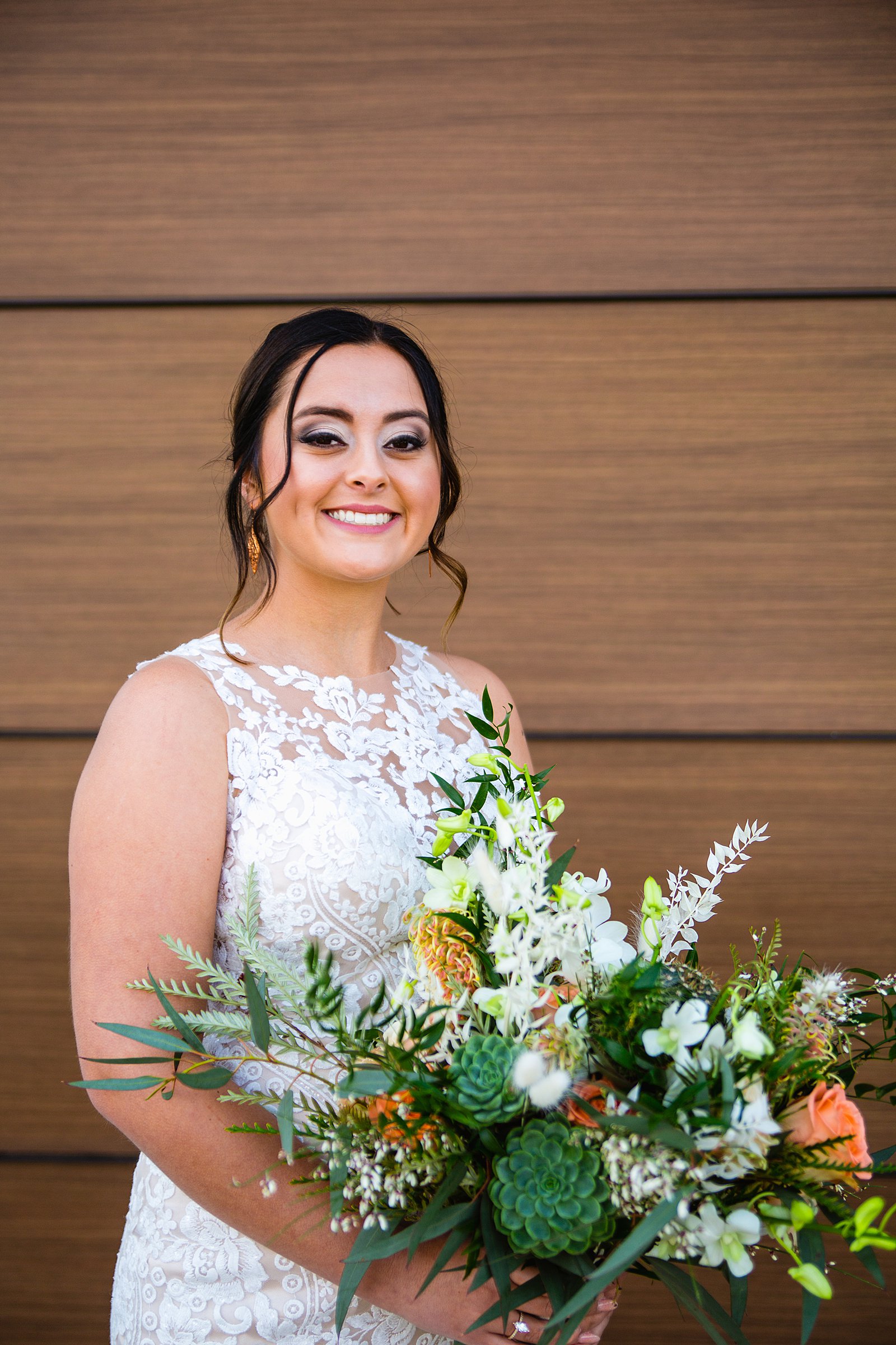Bride with a romantic cream and white wedding dress and a large, wild desert inspired bouquet by Phoenix wedding photographers PMA Photography.