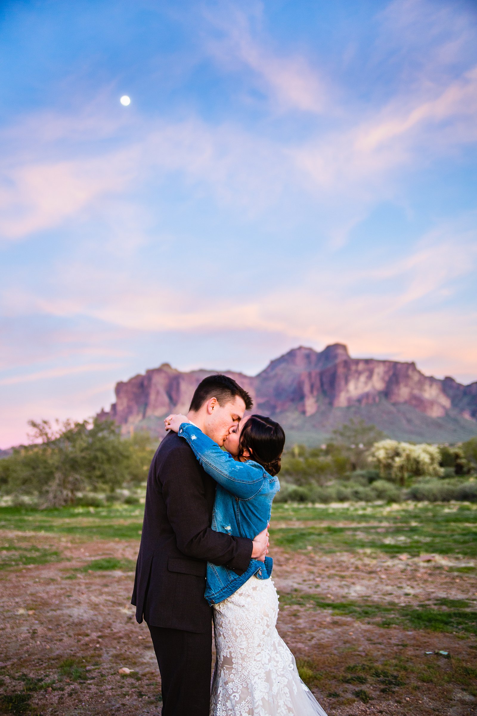 Bride and Groom sharing a kiss at sunset with epic views of the superstition mountains at their The Paseo wedding by Arizona wedding photographer PMA Photography.
