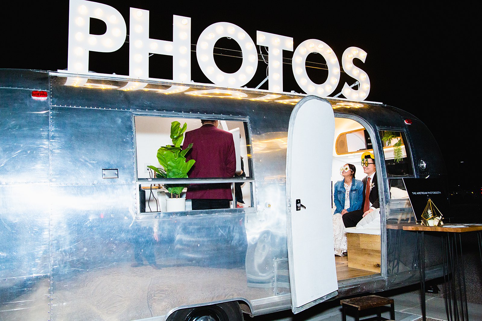 Bride and groom having fun in The Airstream Photo Booth at The Paseo wedding reception by wedding photographer PMA Photography.