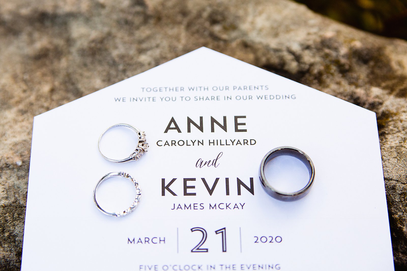 Bride and groom's wedding rings on their wedding invitations by PMA Photography.