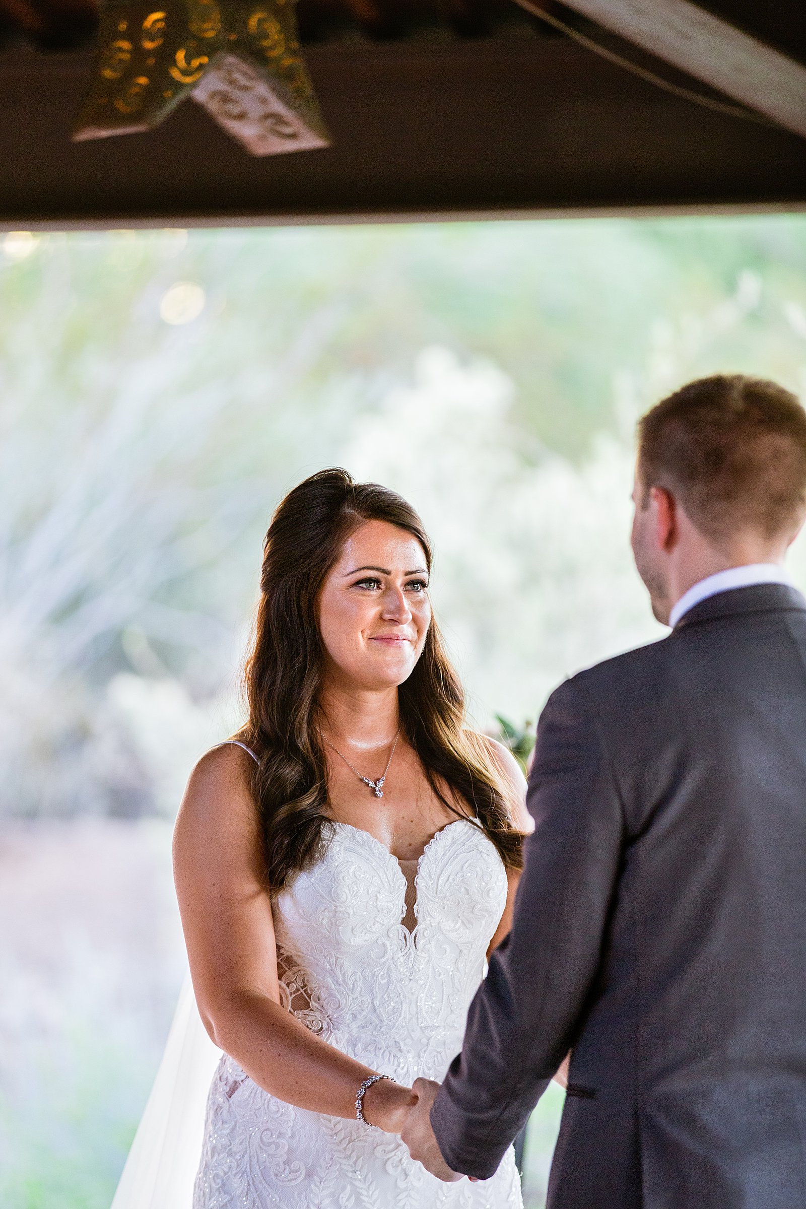 Bride looking at her groom during their wedding ceremony at Desert Botanical Gardens by Phoenix wedding photographer PMA Photography.