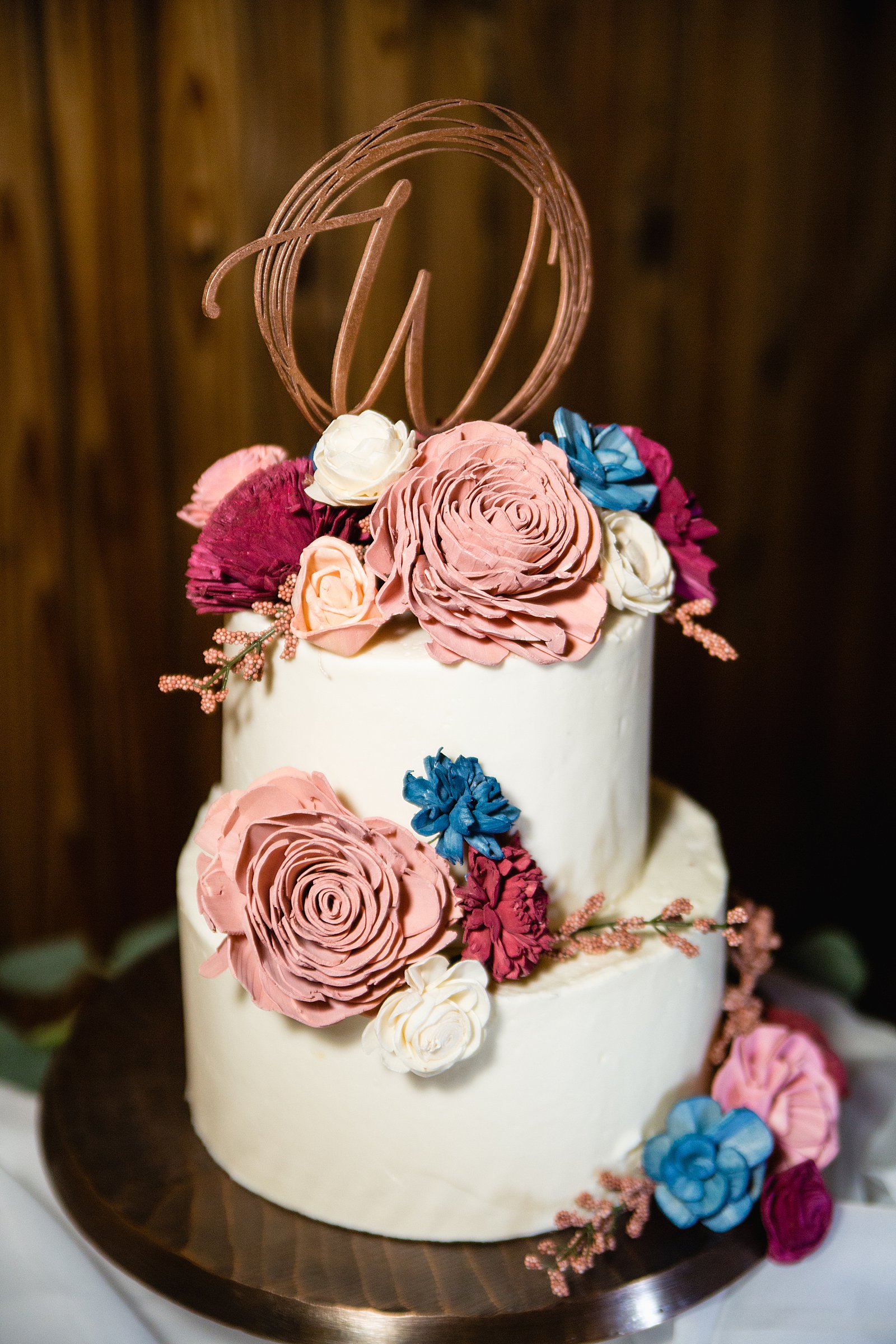 Rustic wedding cake with mauve and navy wooden flowers by Arizona wedding photographer PMA Photography.