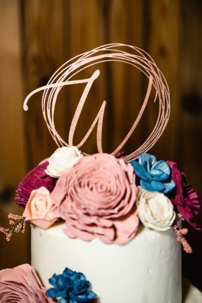 Rustic wedding cake with mauve and navy wooden flowers by Arizona wedding photographer PMA Photography.