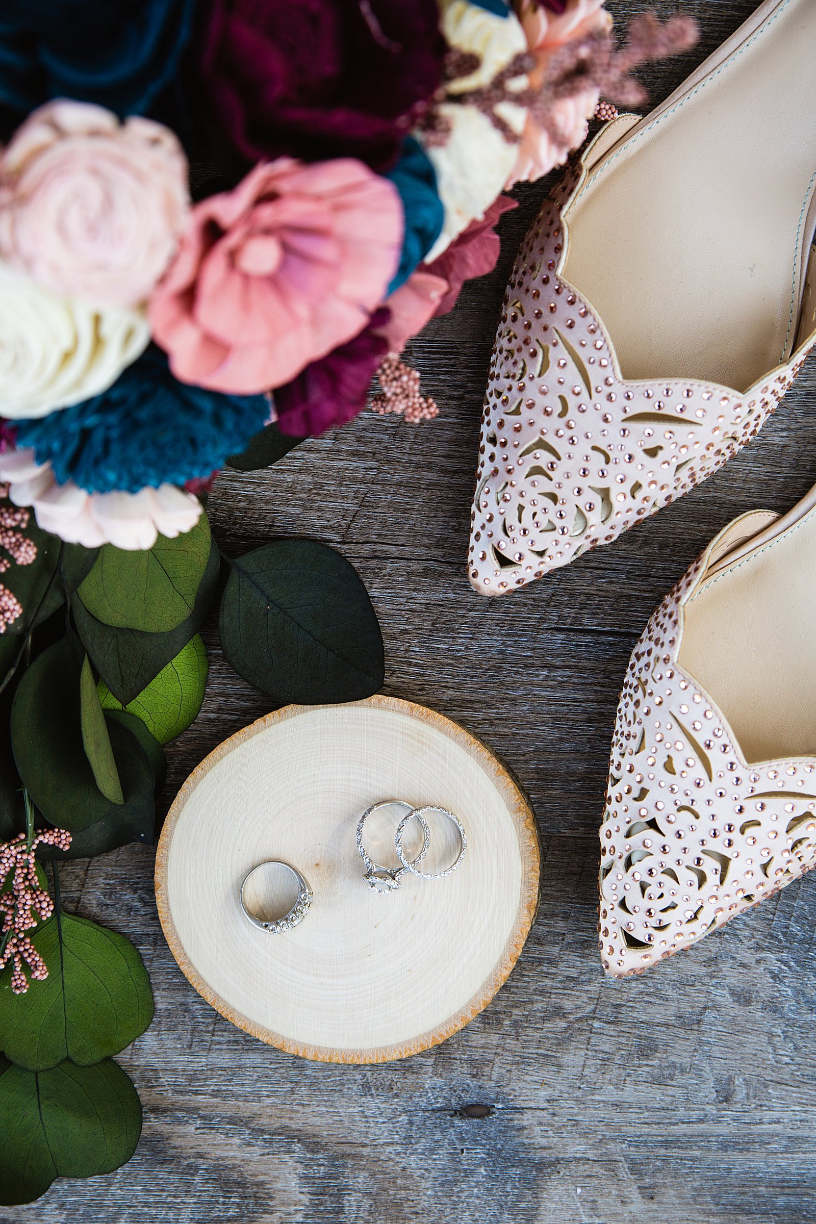 Bride's wedding day details of blush shoes, rings, and colorful wooden flower bouquet by PMA Photography.