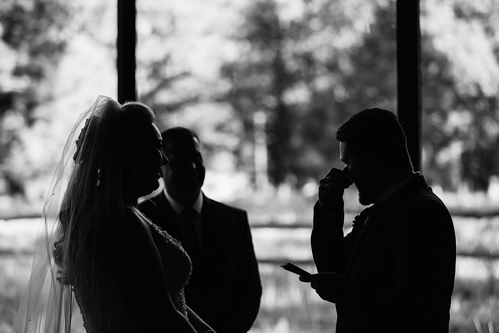 Black and white silhouette image of the groom crying while reading his vows by Arizona wedding photographer PMA Photography.