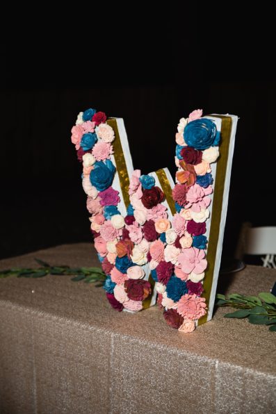Floral W made of wooden flowers reception decorations at backyard wedding reception by Flagstaff wedding photographer PMA Photography.