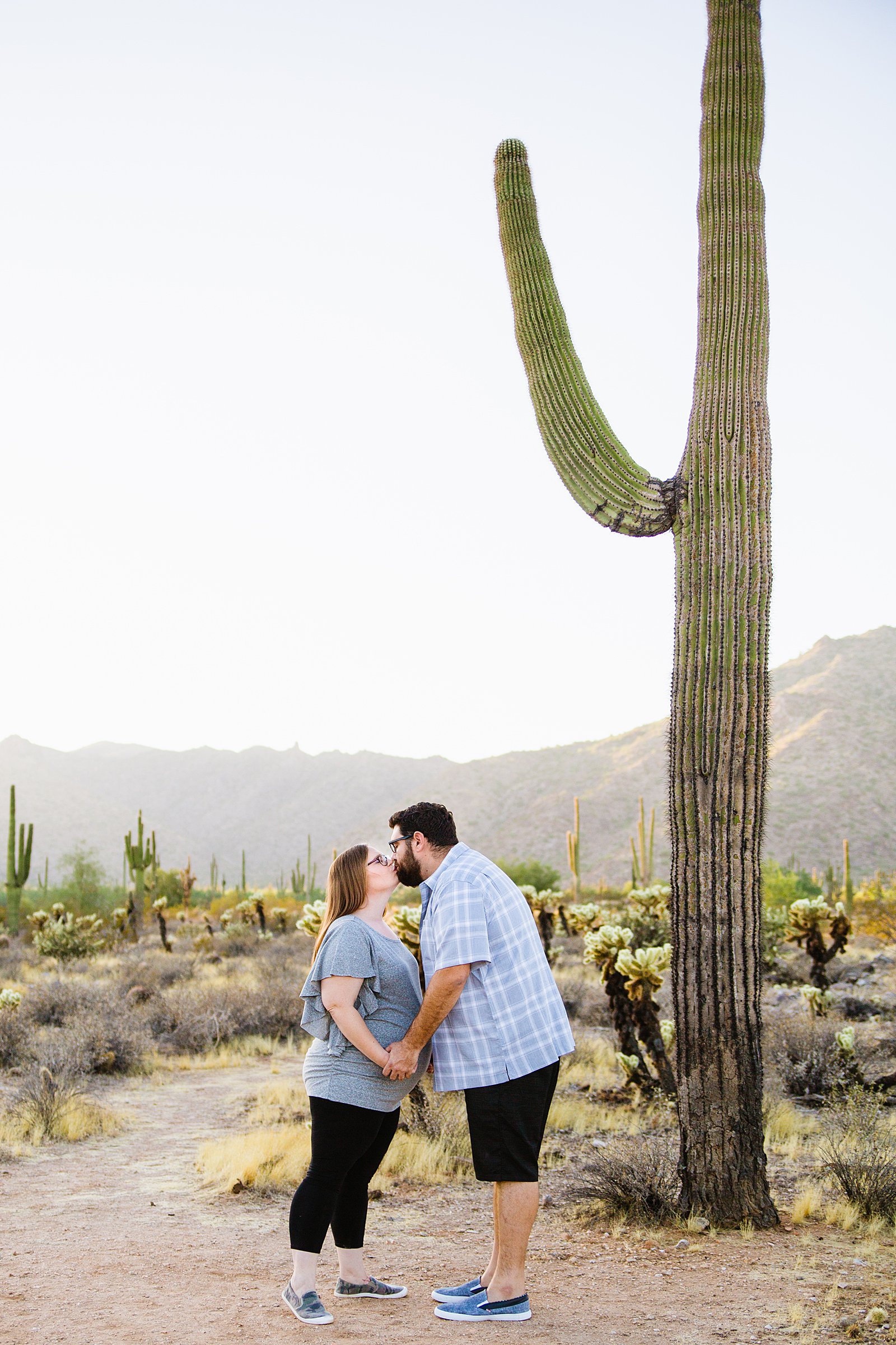 Couple kiss during their maternity session at the White Tanks by Phoenix maternity photographer PMA Photography.