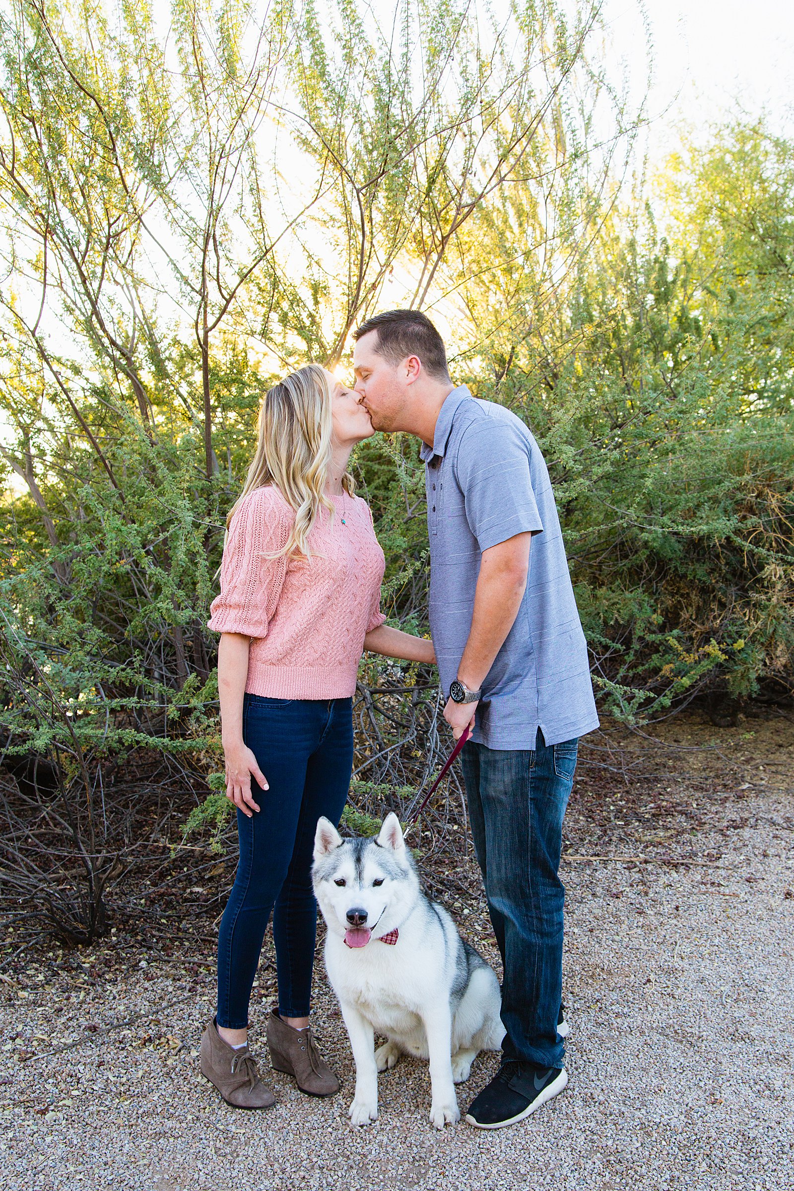 Couple pose with their dog during their Gilbert engagement session by Arizona wedding photographer PMA Photography.