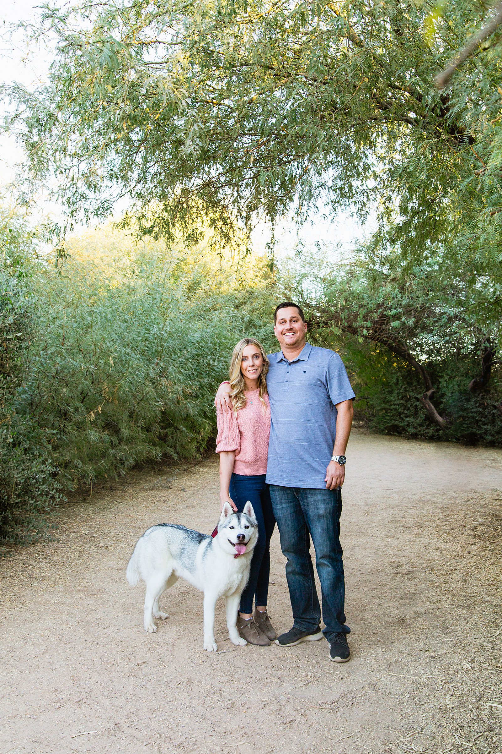 Couple pose with their dog during their Gilbert engagement session by Arizona wedding photographer PMA Photography.