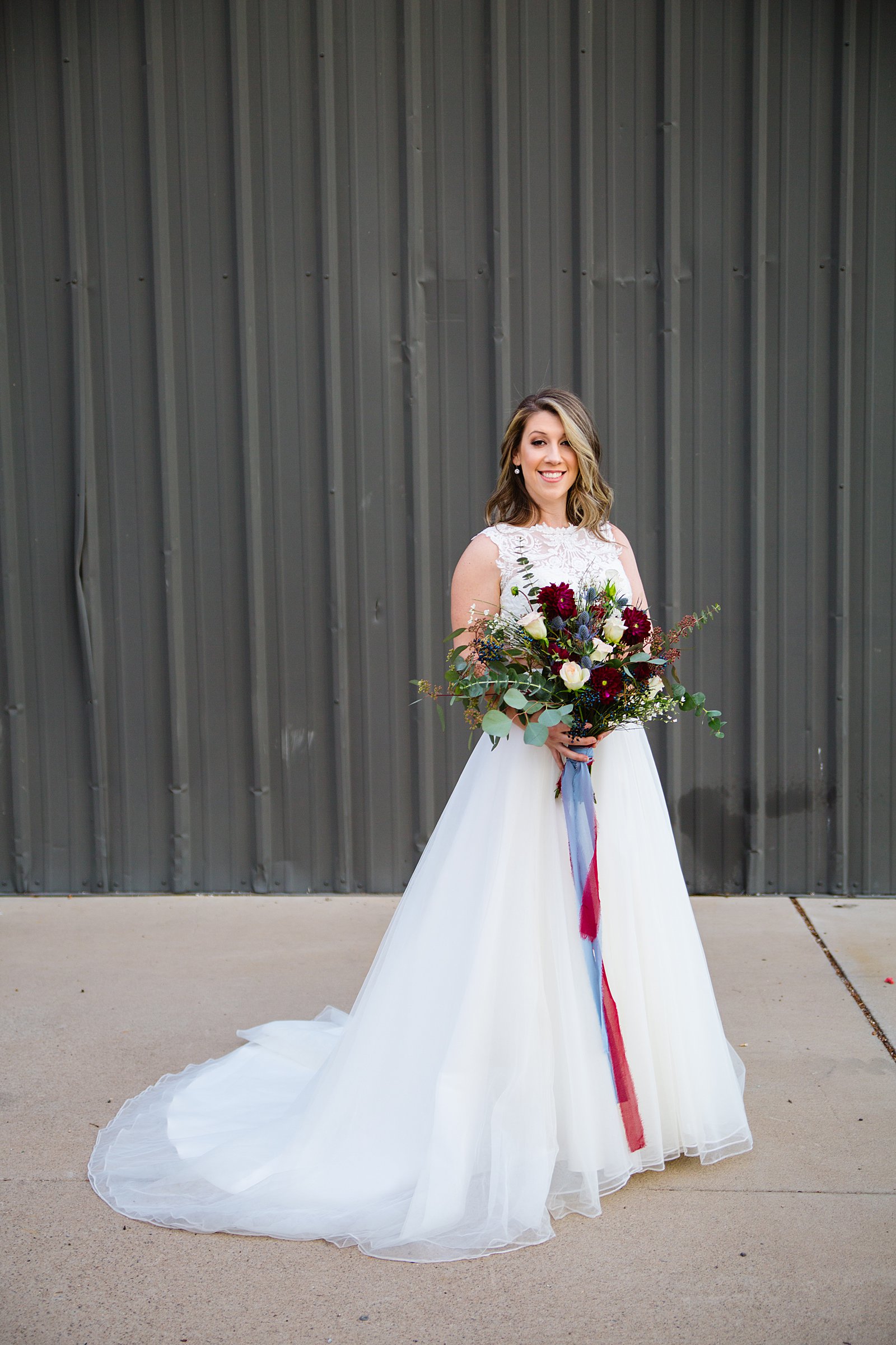 Bride with a simple and romantic wedding dress with a jewel toned bouquet by Phoenix wedding photographers PMA Photography.